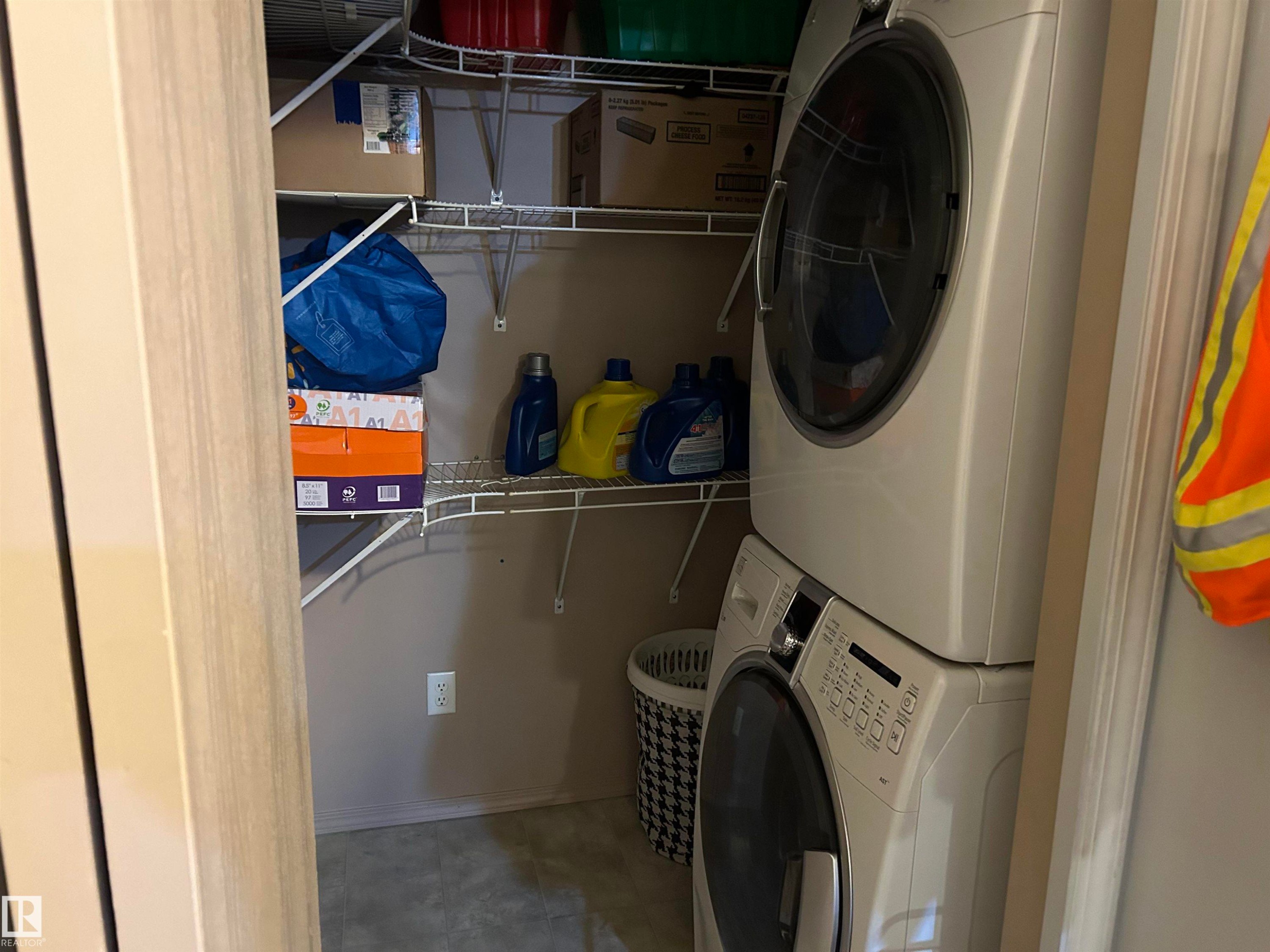 Washroom with stacked washing machine and dryer - 310 2430 Guardian Road, Edmonton, AB - Indoor Photo Showing Laundry Room