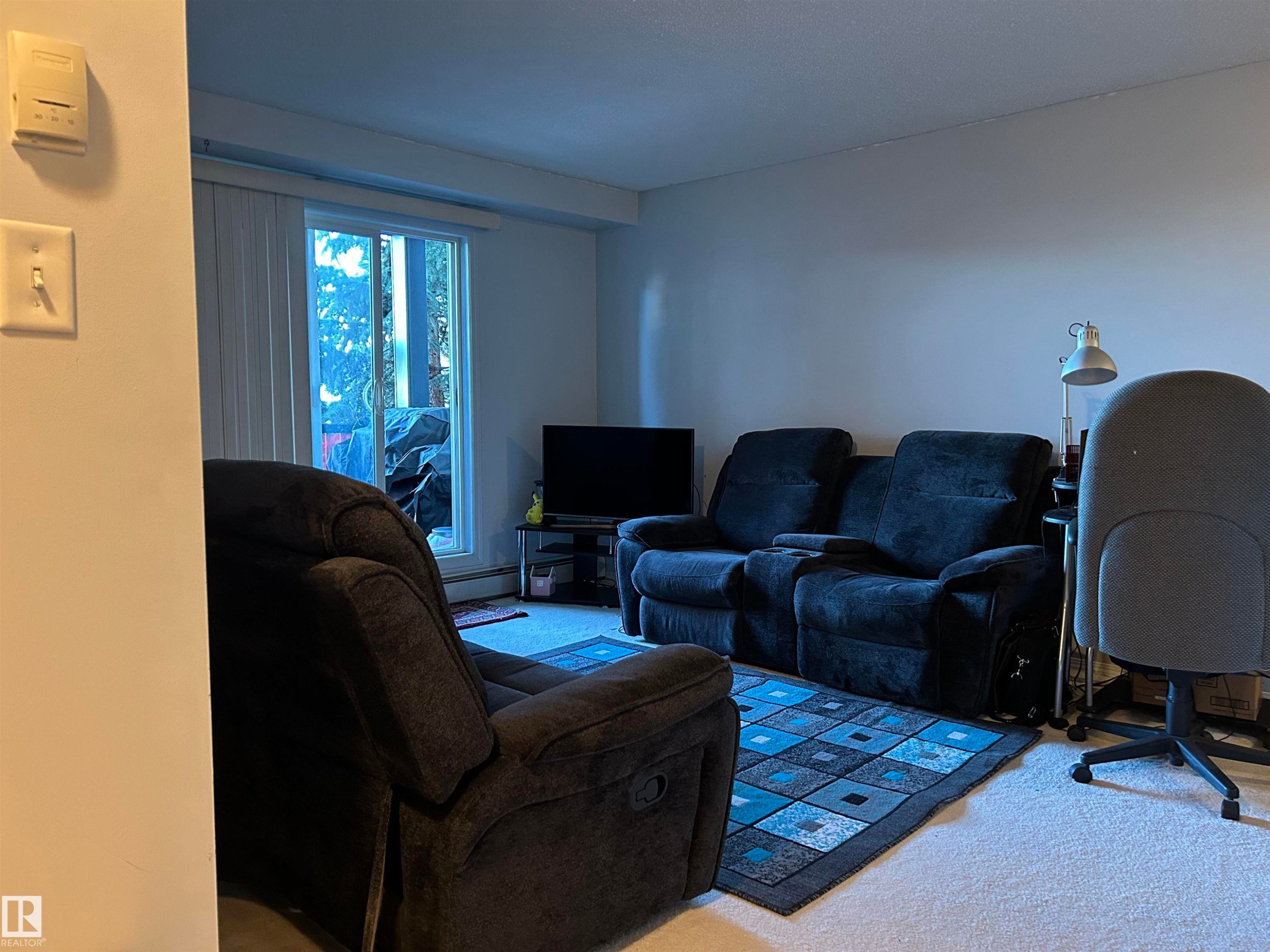 Carpeted living area featuring a baseboard radiator - 310 2430 Guardian Road, Edmonton, AB - Indoor Photo Showing Living Room