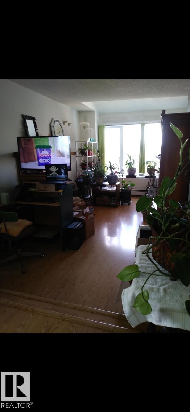 This living space features wood flooring and a large window, providing natural light - 401 10743 107 Street Nw, Edmonton, AB - Indoor