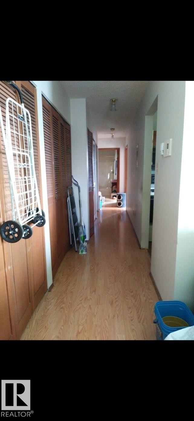 The property features a hallway with wood-look flooring and louvered doors - 401 10743 107 Street Nw, Edmonton, AB - Indoor Photo Showing Other Room