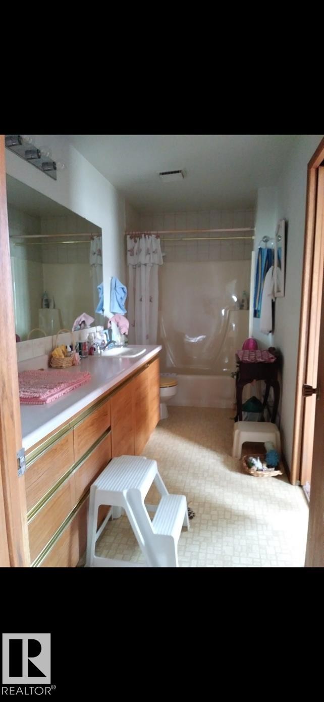 Bathroom featuring a vanity with a countertop and integrated sink, a large wall-mounted mirror, and a bathtub with a shower - 401 10743 107 Street Nw, Edmonton, AB - Indoor