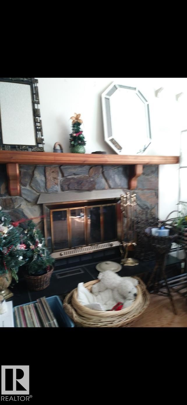 Fireplace with a stone surround, a wooden mantel, and a metal fire screen - 401 10743 107 Street Nw, Edmonton, AB - Outdoor