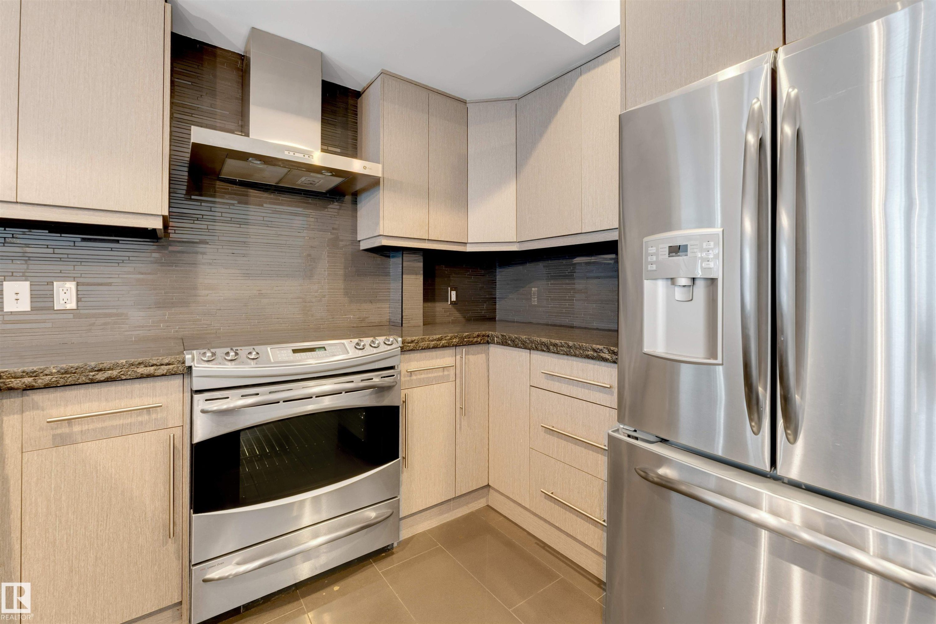 Kitchen with stainless steel appliances, light tile patterned floors, dark stone counters, light wood finish cabinets, and decorative backsplash - 102 10711 83 Avenue, Edmonton, AB - Indoor Photo Showing Kitchen