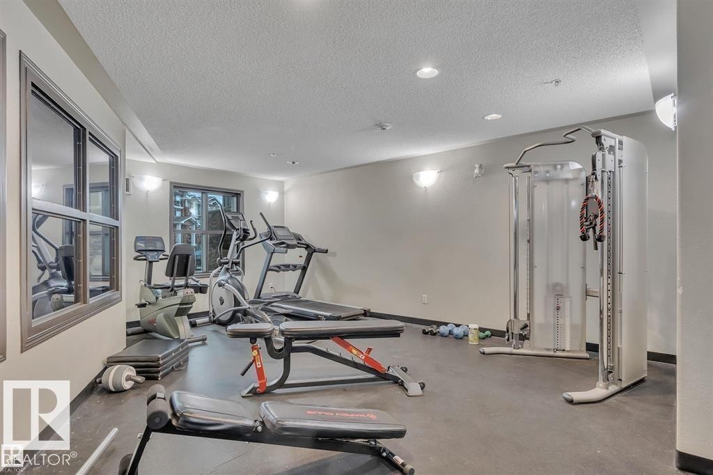 Fitness center featuring a variety of exercise equipment including treadmills, ellipticals, and weight benches, with large windows providing natural light - 3309 9351 Simpson Drive, Edmonton, AB - Indoor Photo Showing Gym Room