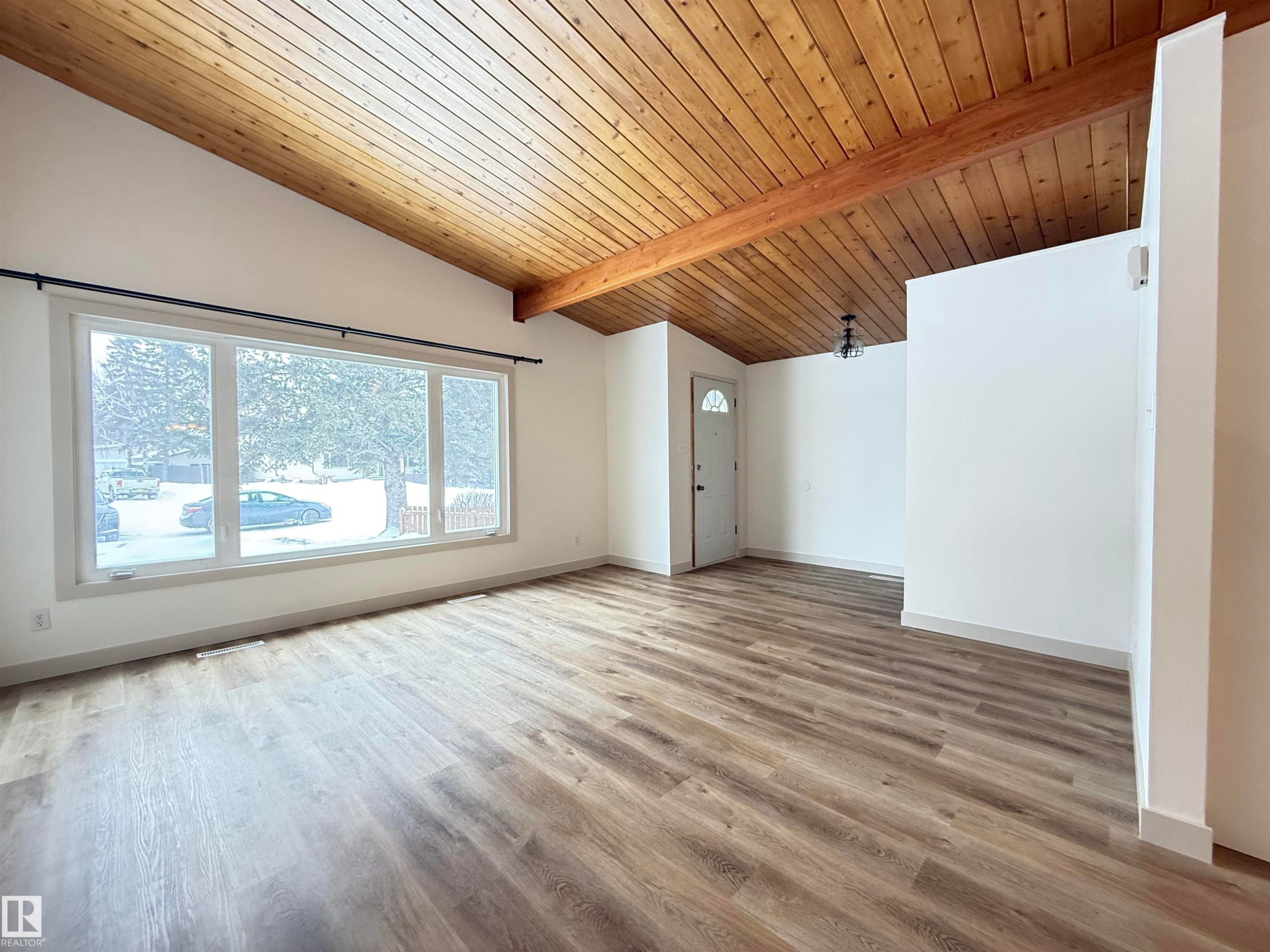 Empty room featuring wood ceiling, light wood finished floors, and lofted ceiling with beams - 9034 60 Street, Edmonton, AB - Indoor