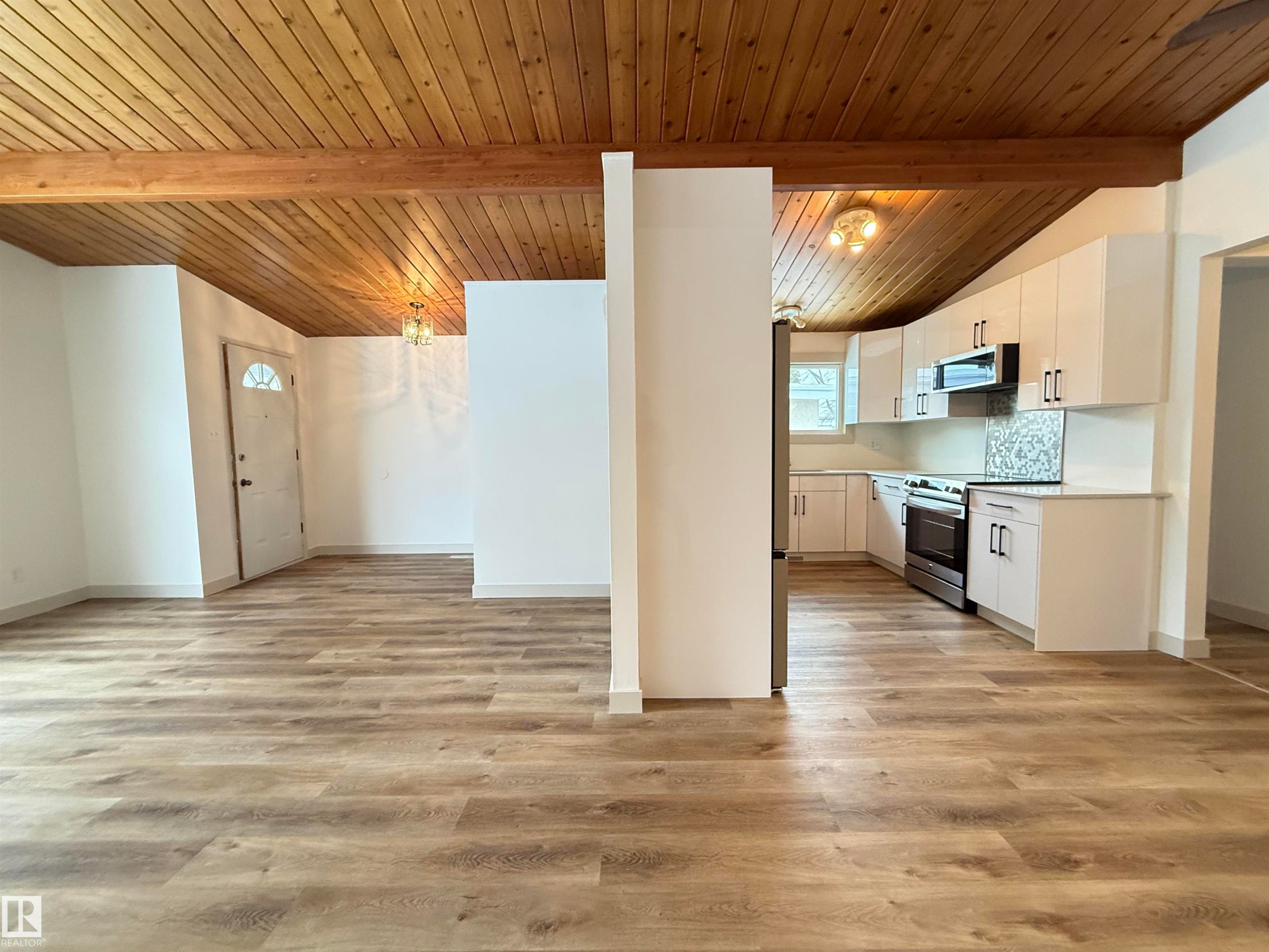 Kitchen featuring white cabinetry, light countertops, stainless steel appliances, light wood-style flooring, and backsplash - 9034 60 Street, Edmonton, AB - Indoor Photo Showing Kitchen