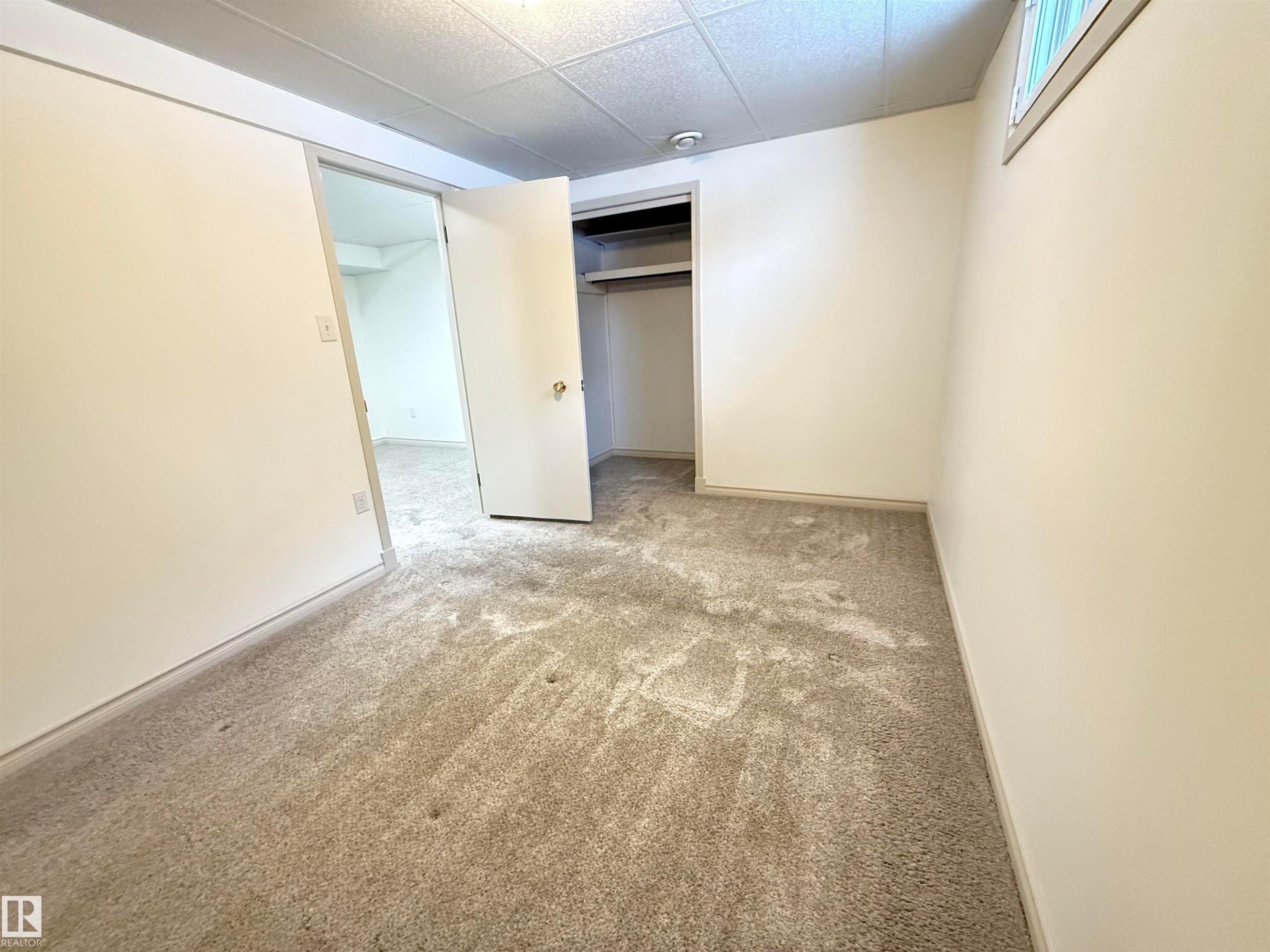 Unfurnished bedroom with light carpet, a closet, and a drop ceiling - 9034 60 Street, Edmonton, AB - Indoor Photo Showing Other Room