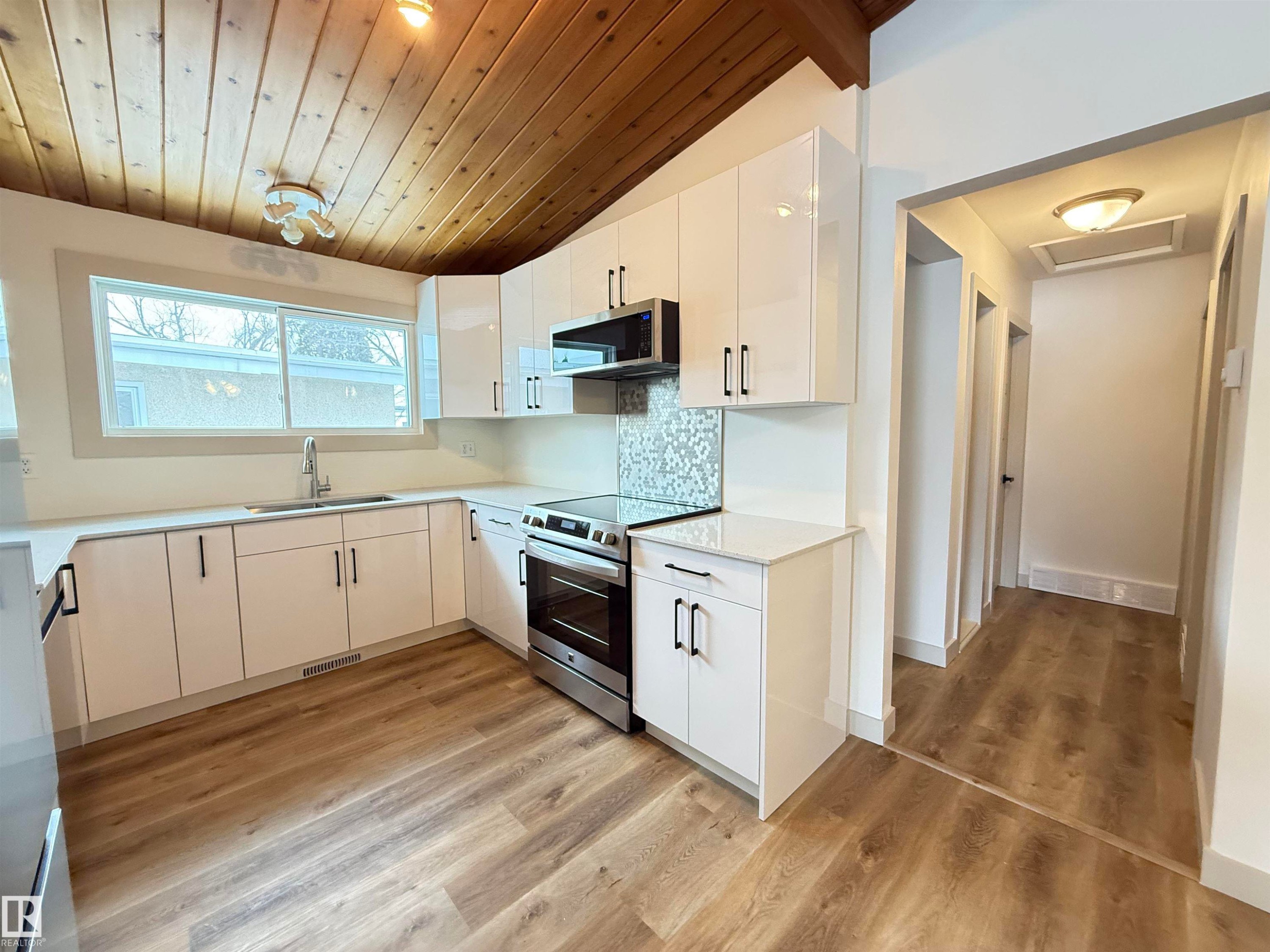Kitchen featuring stainless steel appliances, a vaulted wooden ceiling, backsplash, white cabinetry, and light wood-style floors - 9034 60 Street, Edmonton, AB - Indoor Photo Showing Kitchen With Double Sink With Upgraded Kitchen