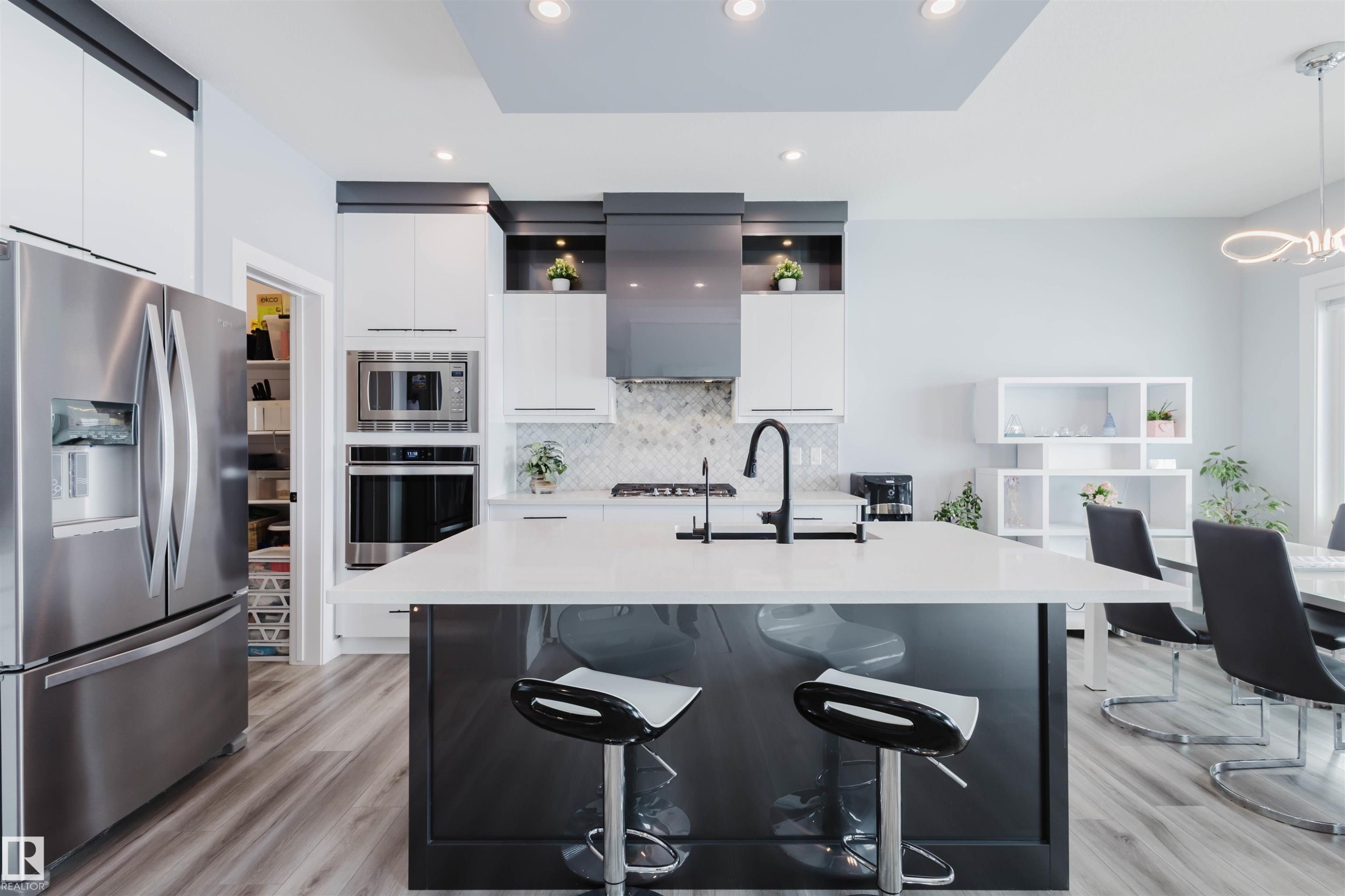 Kitchen featuring stainless steel appliances, a breakfast bar, white cabinetry, modern cabinets, and light wood finished floors - 16217 32 Avenue, Edmonton, AB - Indoor Photo Showing Kitchen With Upgraded Kitchen