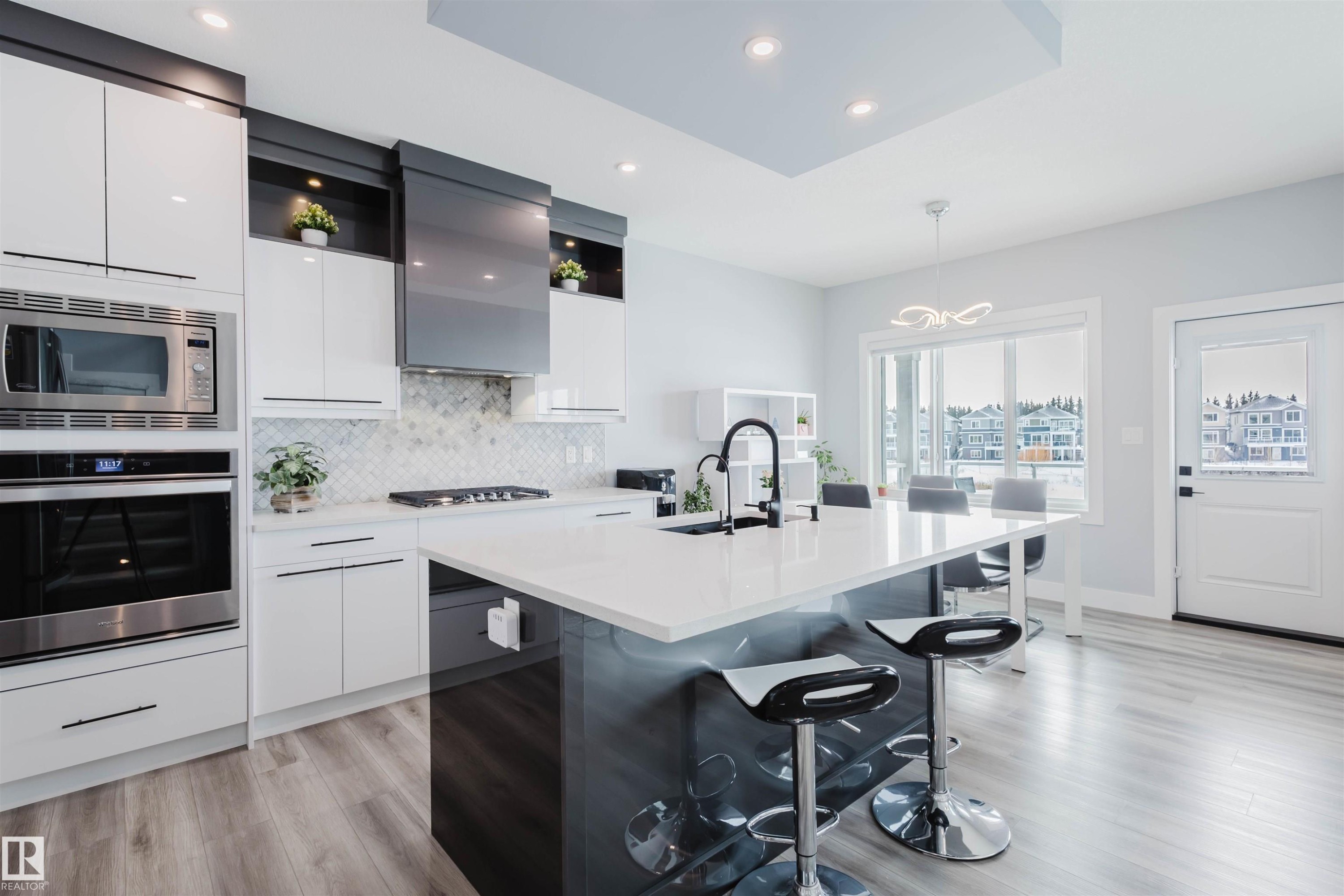 Dual tone kitchen featuring a kitchen bar, stainless steel appliances, modern cabinets, dual tone cabinetry, and a center island with sink - 16217 32 Avenue, Edmonton, AB - Indoor Photo Showing Kitchen With Upgraded Kitchen