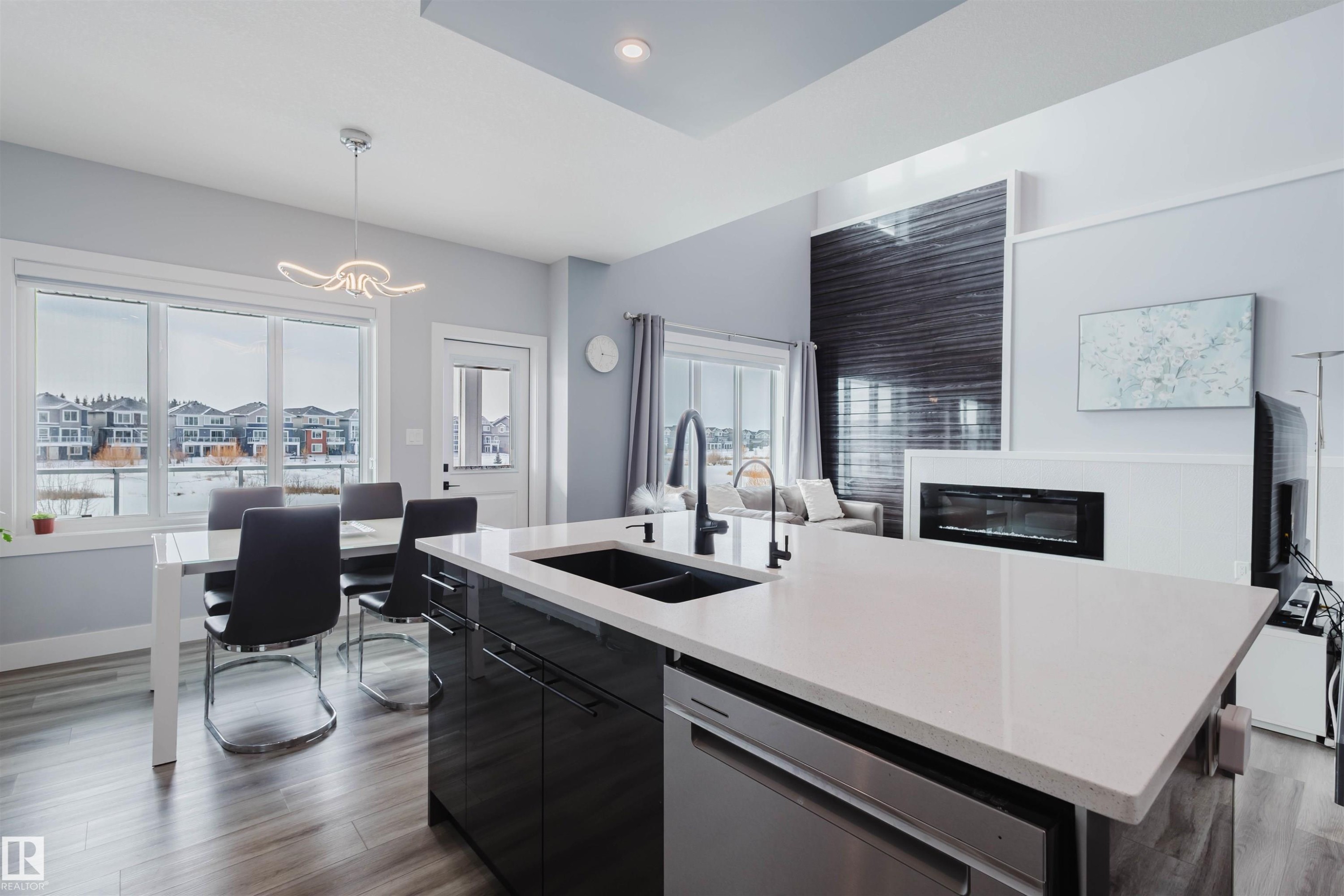 Kitchen featuring dark cabinetry, dark wood-style flooring, an island with sink, dishwasher, and open floor plan - 16217 32 Avenue, Edmonton, AB - Indoor Photo Showing Kitchen With Fireplace With Double Sink