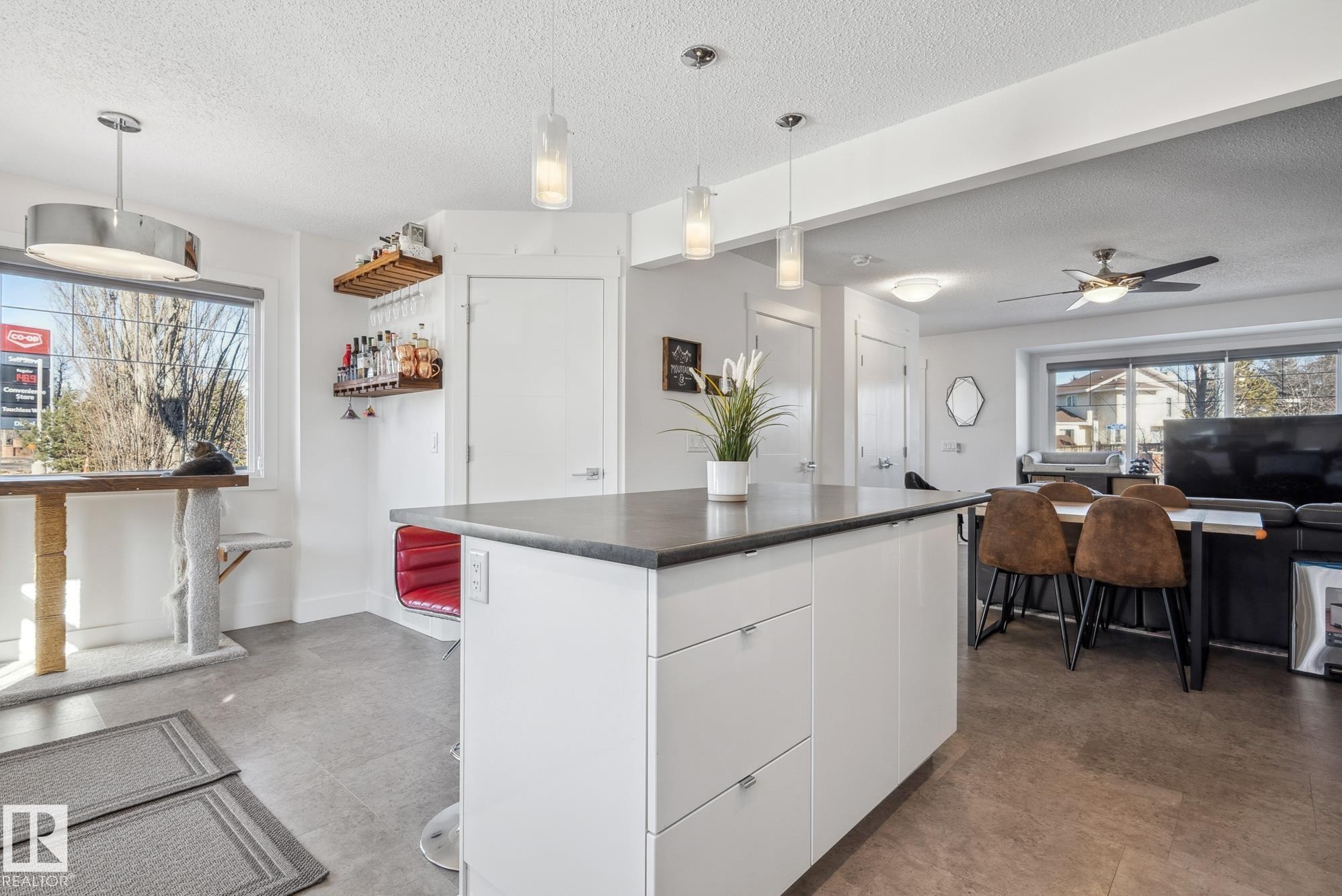 Kitchen with white cabinets, dark countertops, pendant lighting, modern cabinets, and a textured ceiling - 76 330 Bulyea Road, Edmonton, AB - Indoor