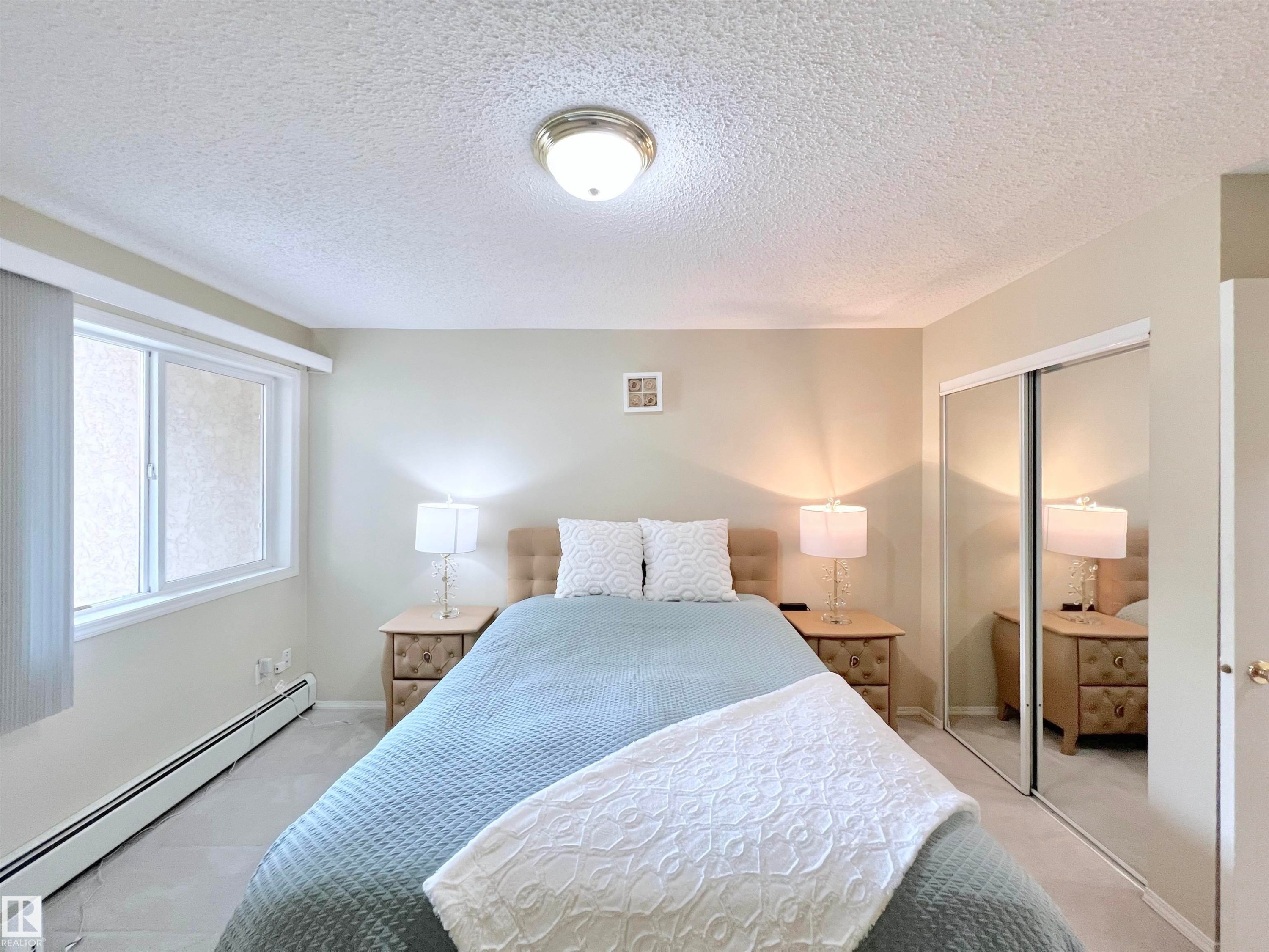 Bedroom featuring baseboard heating, a textured ceiling, and a closet - 110 10511 42 Avenue, Edmonton, AB - Indoor Photo Showing Bedroom