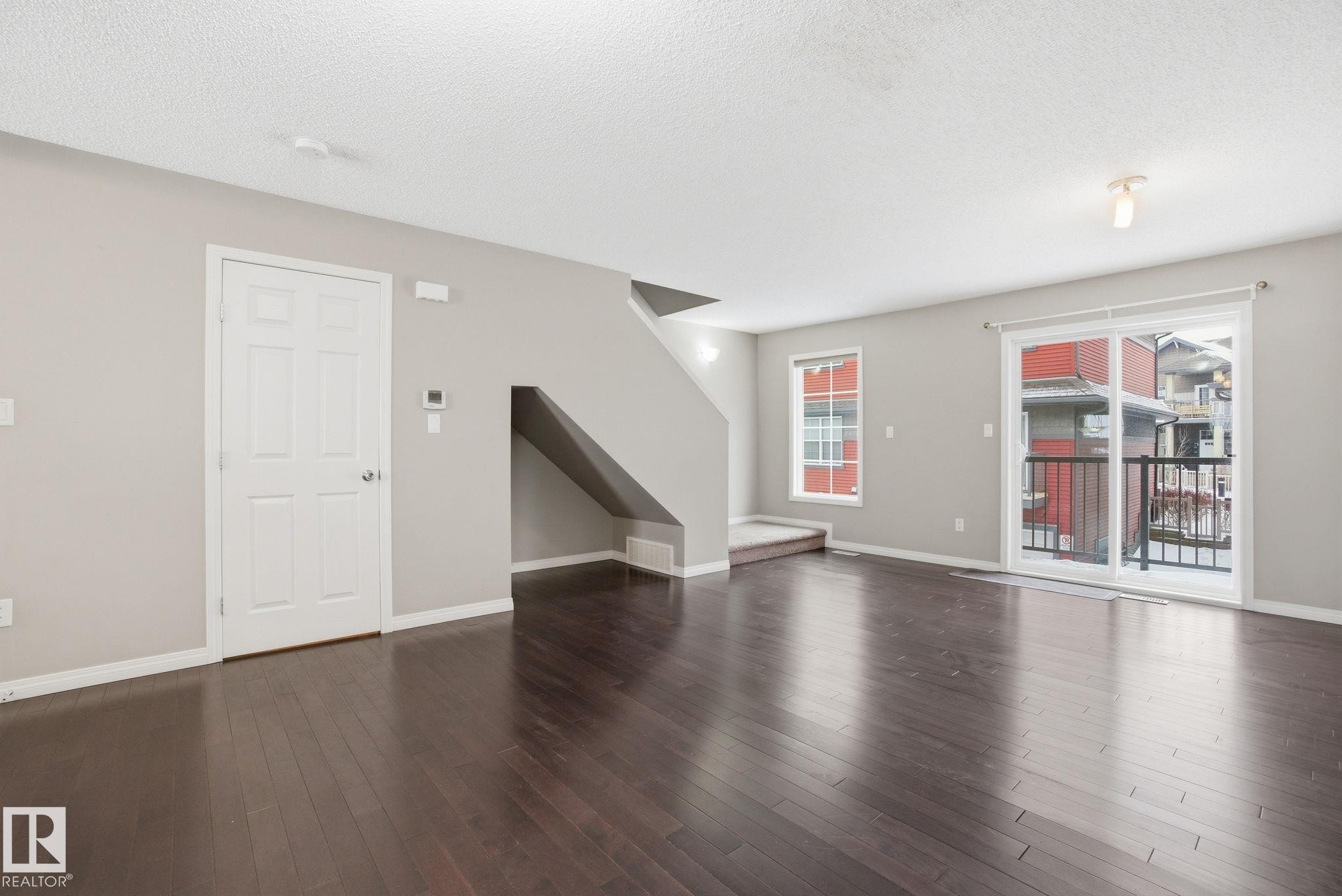 Unfurnished living room with dark wood-type flooring and a textured ceiling - 71 4029 Orchards Drive, Edmonton, AB - Indoor