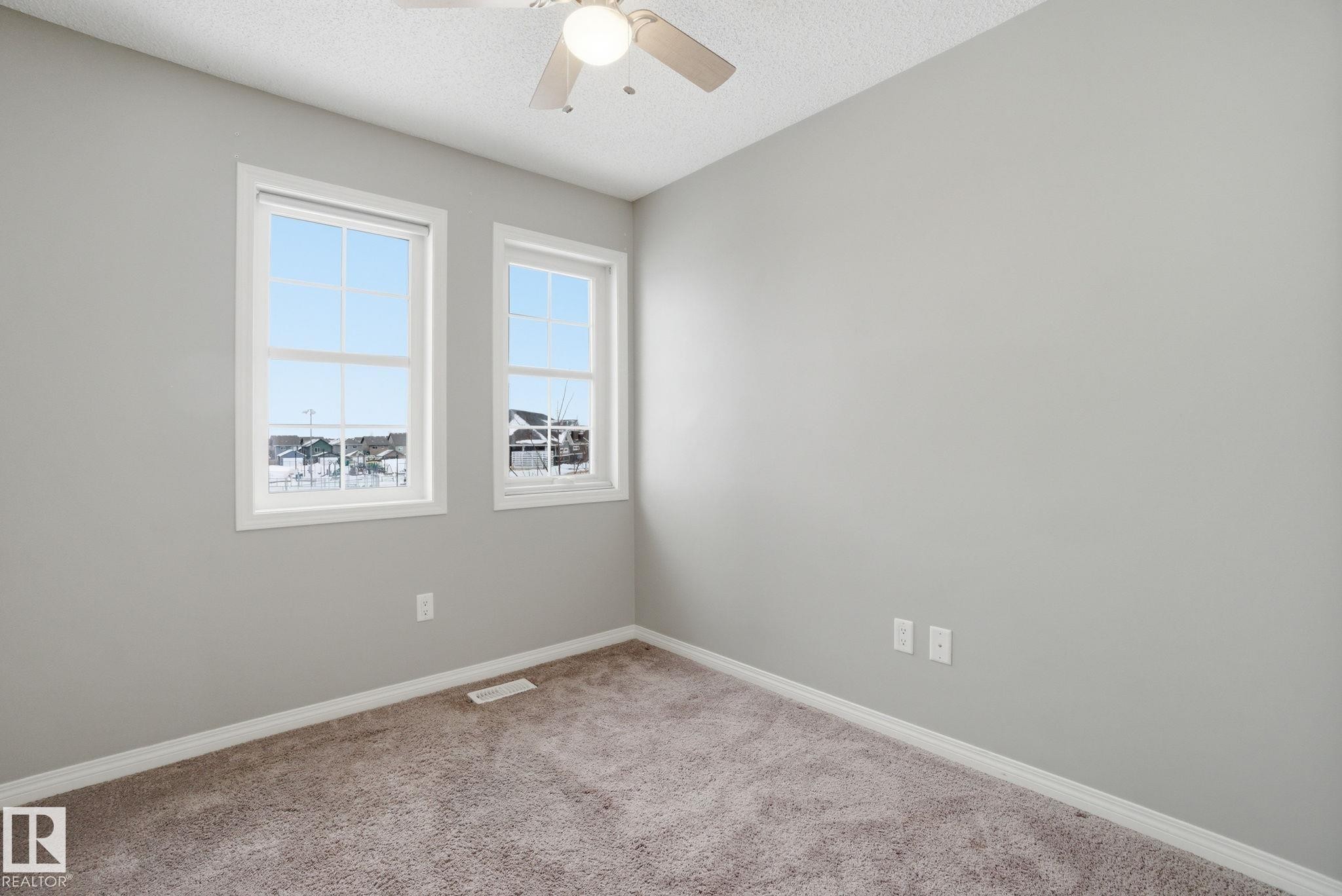 Empty room featuring light colored carpet, a textured ceiling, and a ceiling fan - 71 4029 Orchards Drive, Edmonton, AB - Indoor Photo Showing Other Room