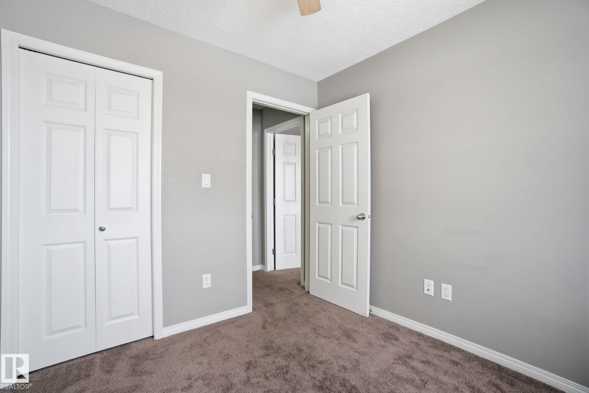 Unfurnished bedroom with a textured ceiling, carpet, a closet, and ceiling fan - 71 4029 Orchards Drive, Edmonton, AB - Indoor Photo Showing Other Room