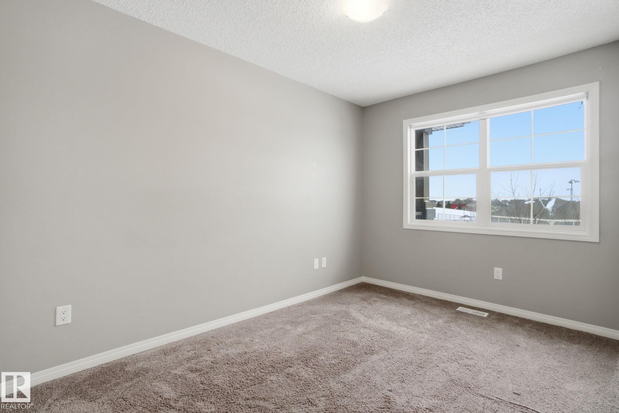 Empty room with light colored carpet and a textured ceiling - 71 4029 Orchards Drive, Edmonton, AB - Indoor Photo Showing Other Room
