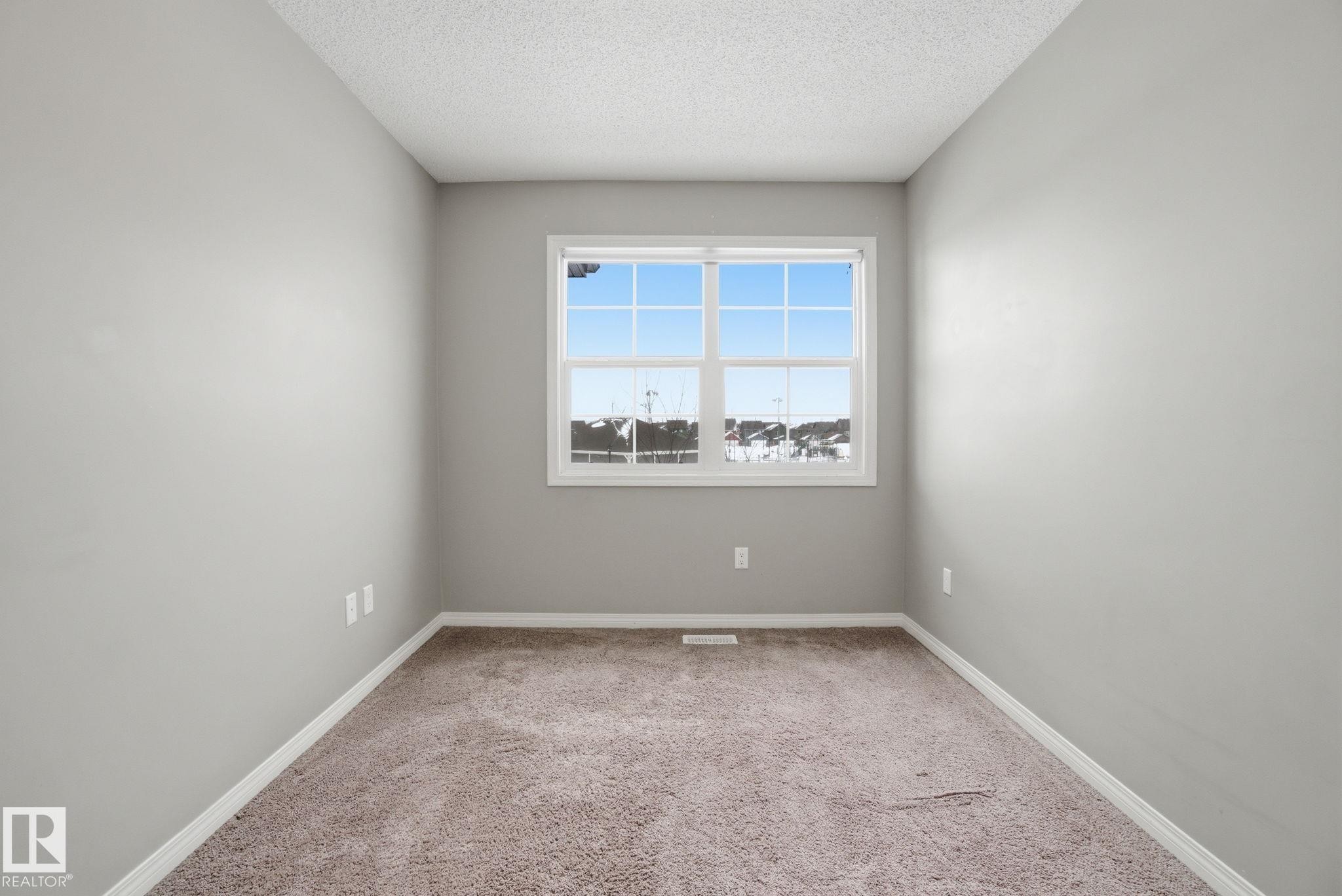 Empty room with light carpet and a textured ceiling - 71 4029 Orchards Drive, Edmonton, AB - Indoor Photo Showing Other Room