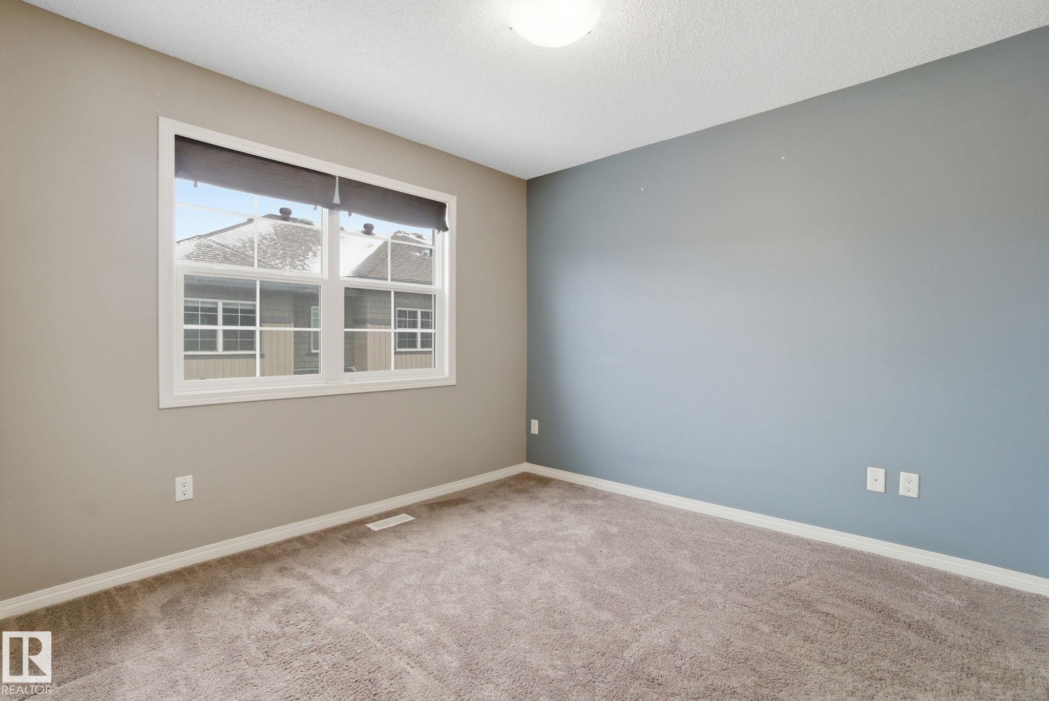Spare room featuring light colored carpet and a textured ceiling - 71 4029 Orchards Drive, Edmonton, AB - Indoor Photo Showing Other Room