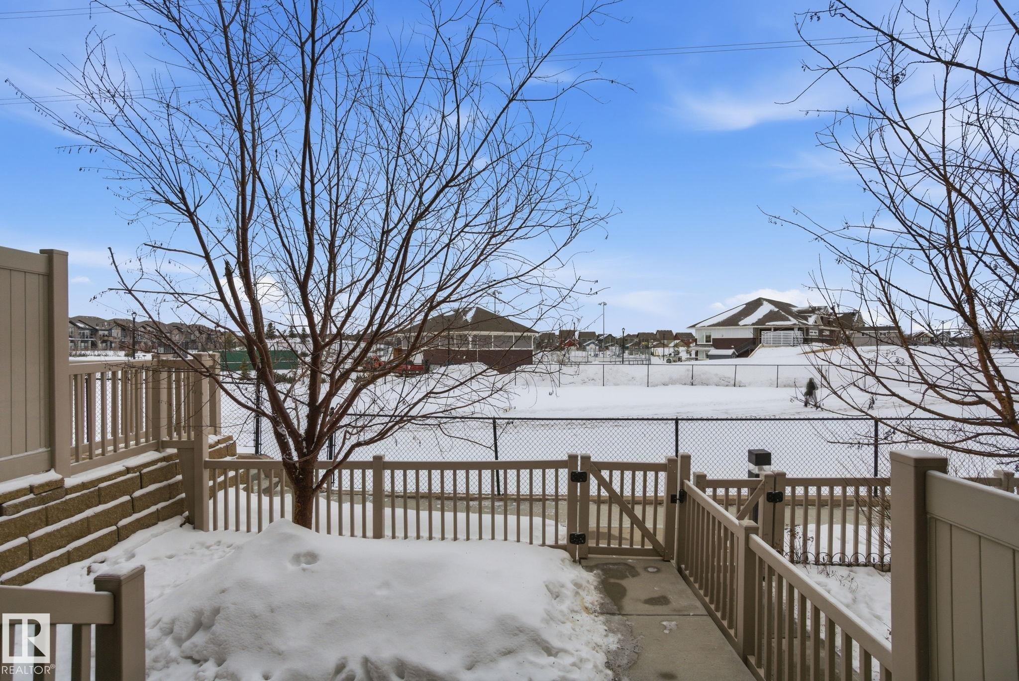 Snow covered patio with a deck and a residential view - 71 4029 Orchards Drive, Edmonton, AB - Outdoor