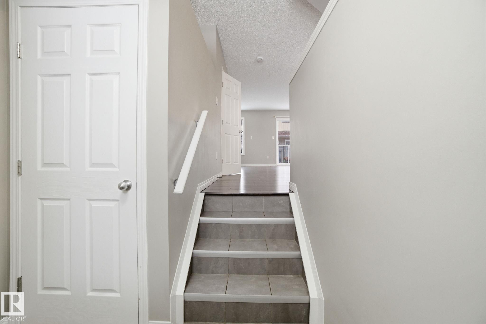 Stairway featuring a textured ceiling and tile patterned floors - 71 4029 Orchards Drive, Edmonton, AB - Indoor Photo Showing Other Room