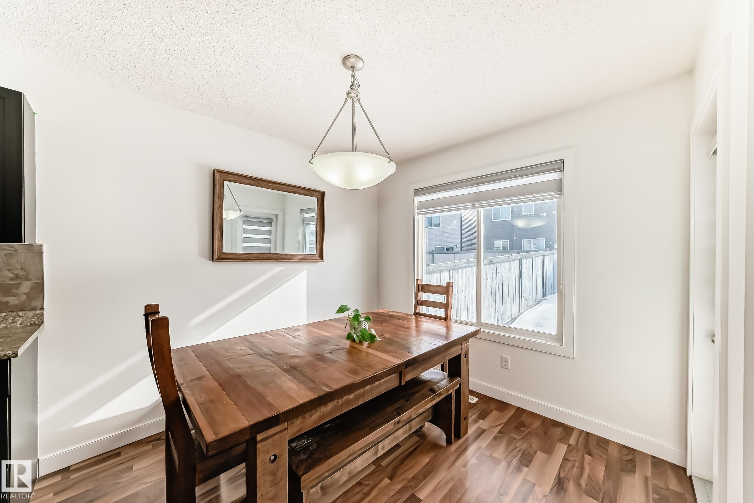 Dining space featuring wood finished floors and a textured ceiling - 17357 8A Avenue, Edmonton, AB