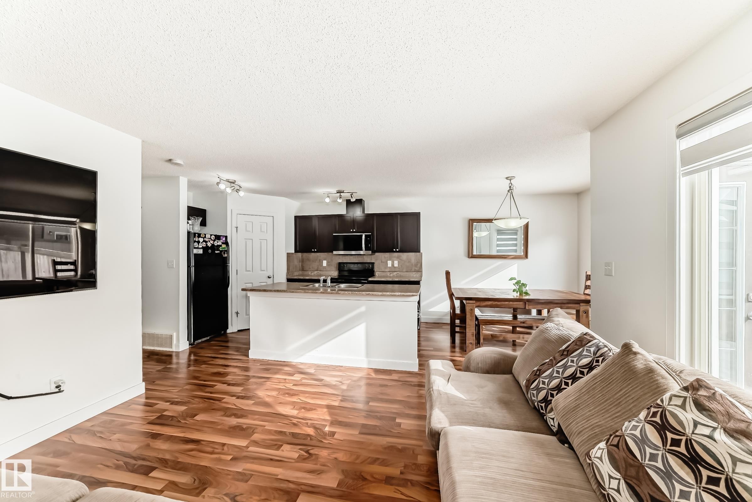 Living room with dark wood-style floors and a textured ceiling - 17357 8A Avenue, Edmonton, AB