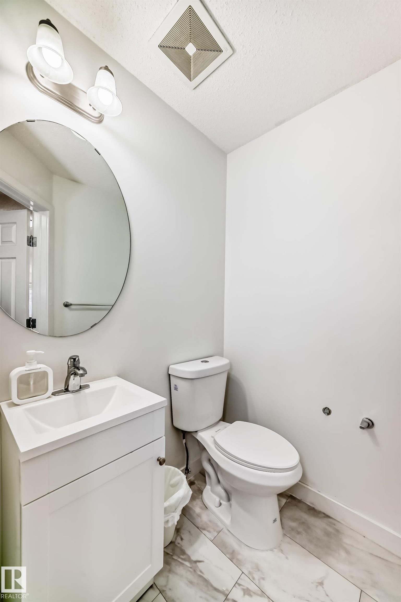 Half bath featuring vanity, light marble finish floors, and a textured ceiling - 17357 8A Avenue, Edmonton, AB