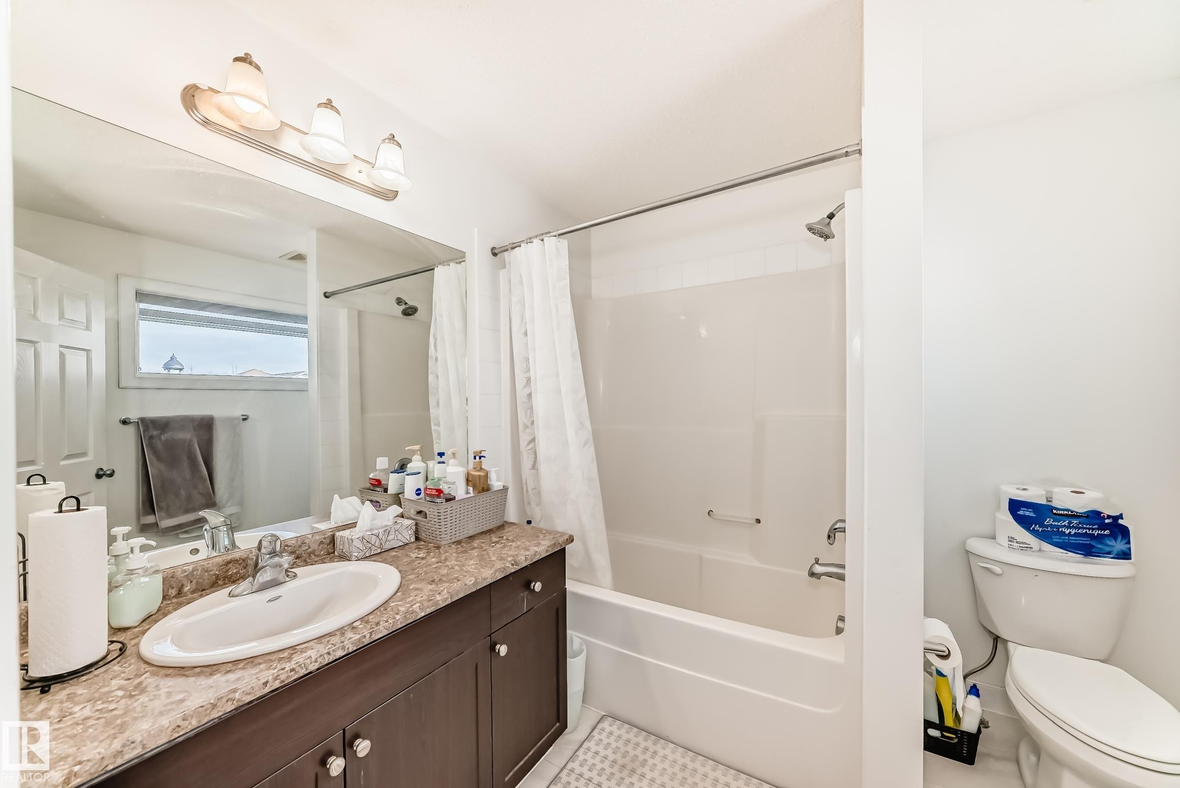 Bathroom featuring vanity, shower / bath combo with shower curtain, and light tile patterned flooring - 17357 8A Avenue, Edmonton, AB