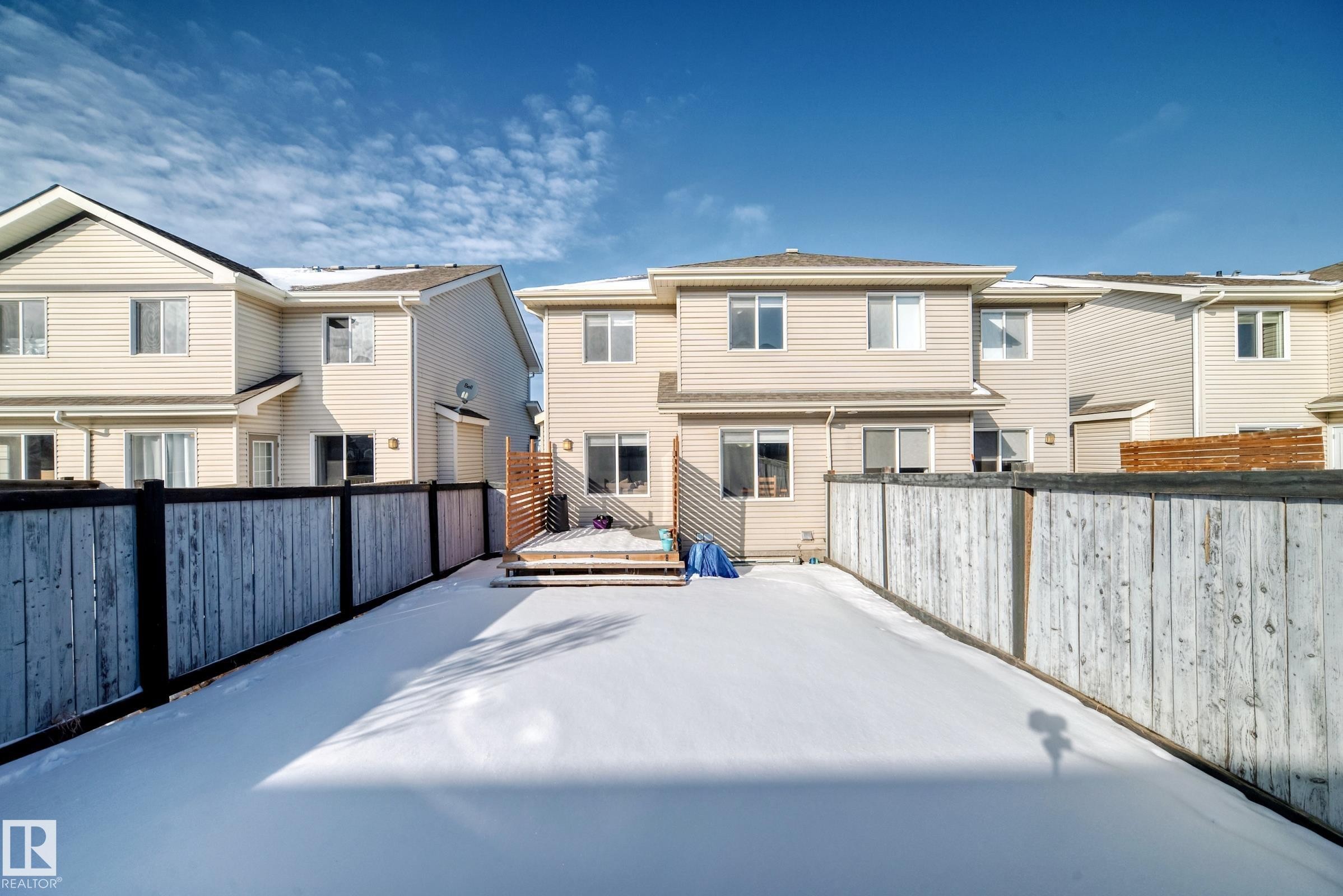 Snow covered back of property with a fenced backyard, a deck, and a residential view - 17357 8A Avenue, Edmonton, AB