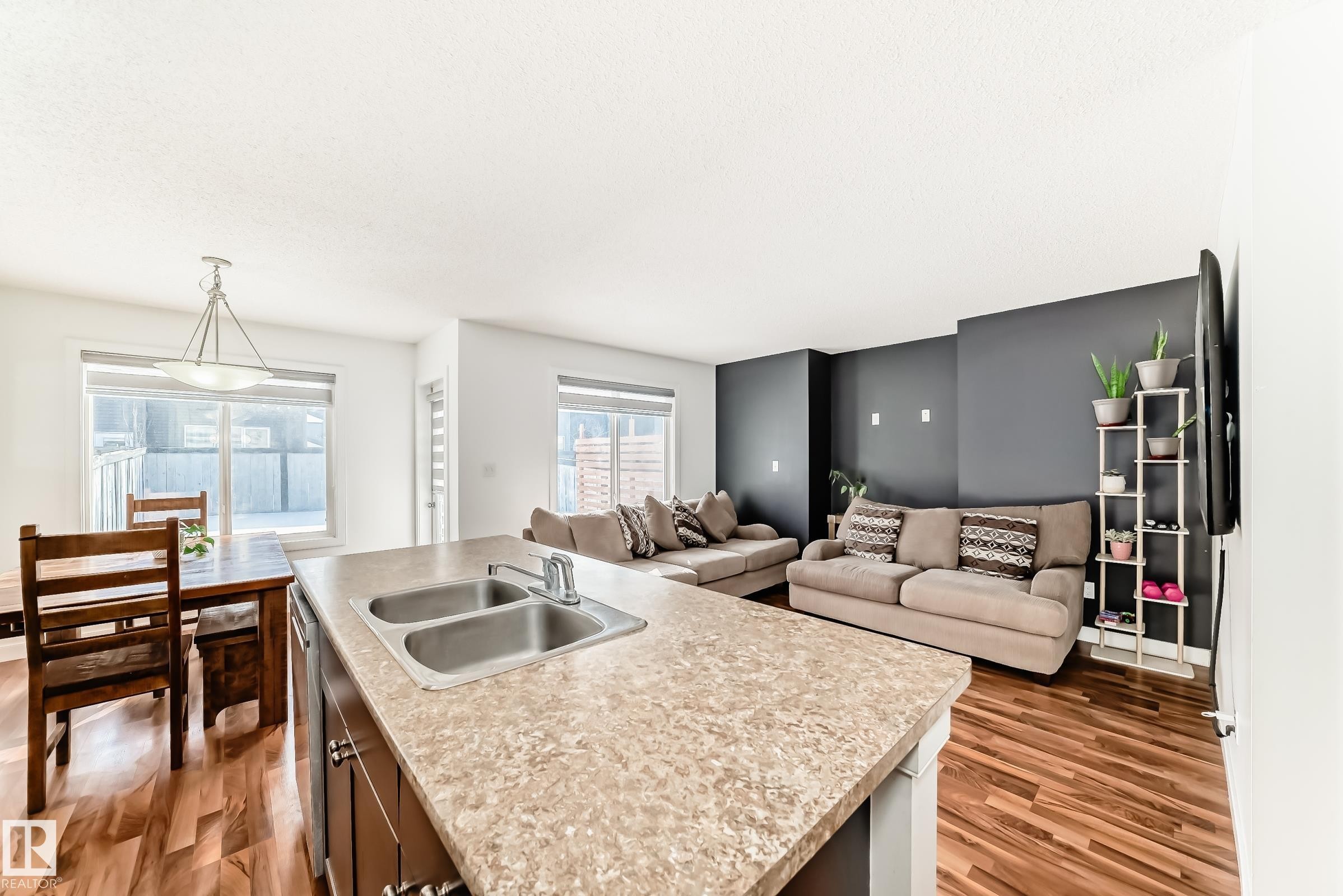 Kitchen featuring light countertops, open floor plan, a kitchen island with sink, and light wood-type flooring - 17357 8A Avenue, Edmonton, AB