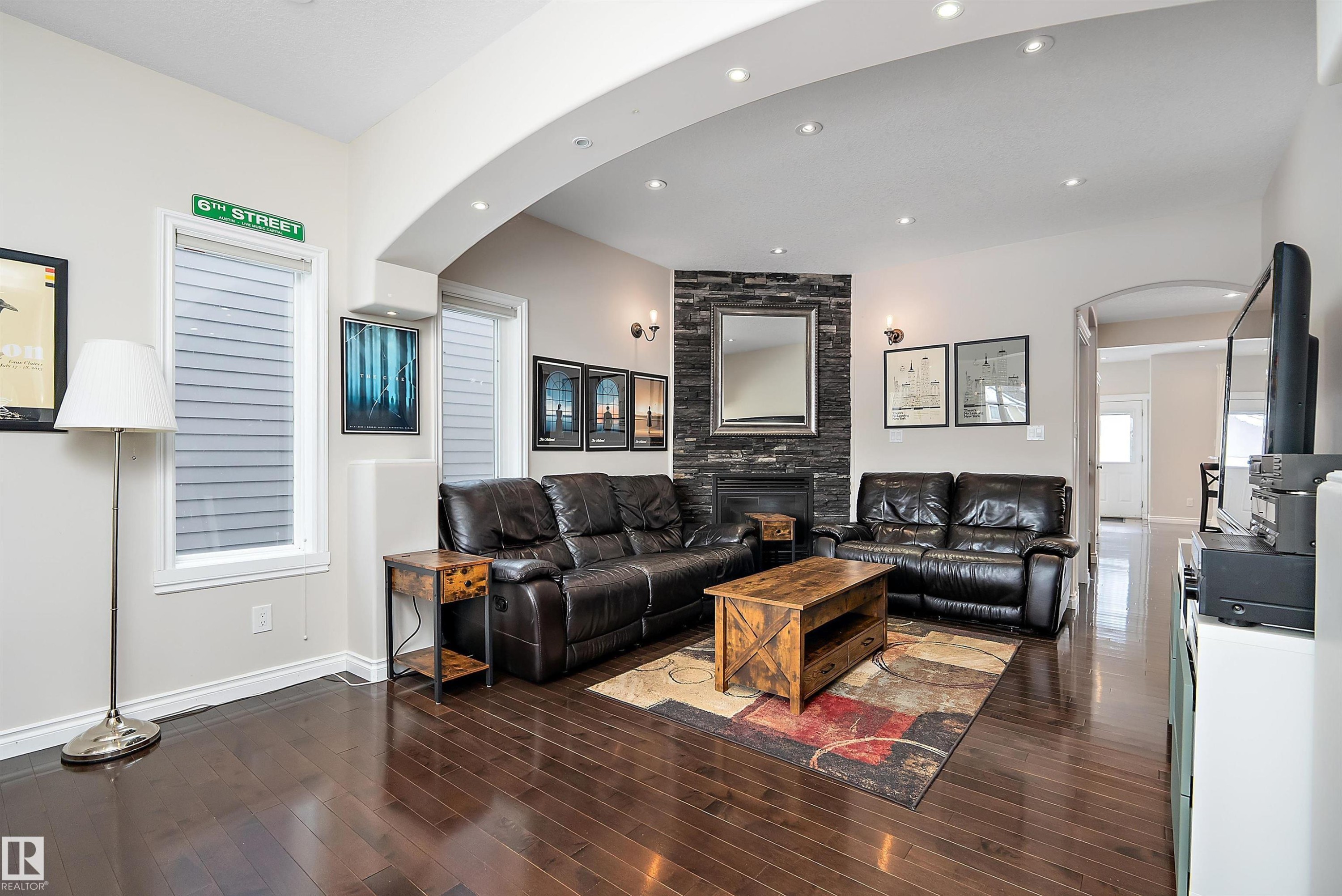 Living room featuring arched walkways, dark wood-type flooring, a fireplace, and recessed lighting - 10623 75 Avenue, Edmonton, AB - Indoor Photo Showing Living Room With Fireplace