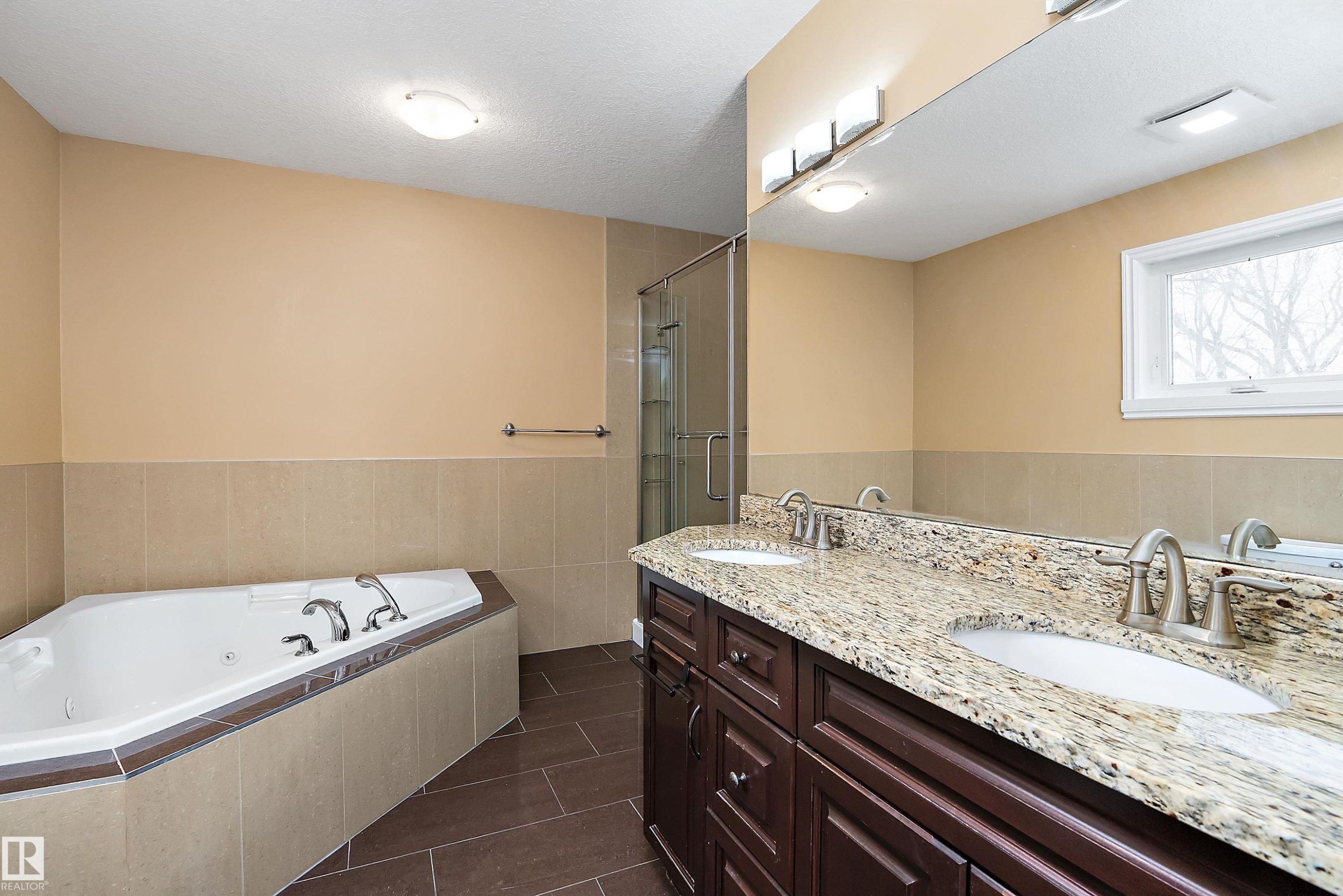 Full bathroom featuring a jetted tub, double vanity, dark tile patterned floors, a textured ceiling, and a stall shower - 10623 75 Avenue, Edmonton, AB - Indoor Photo Showing Bathroom