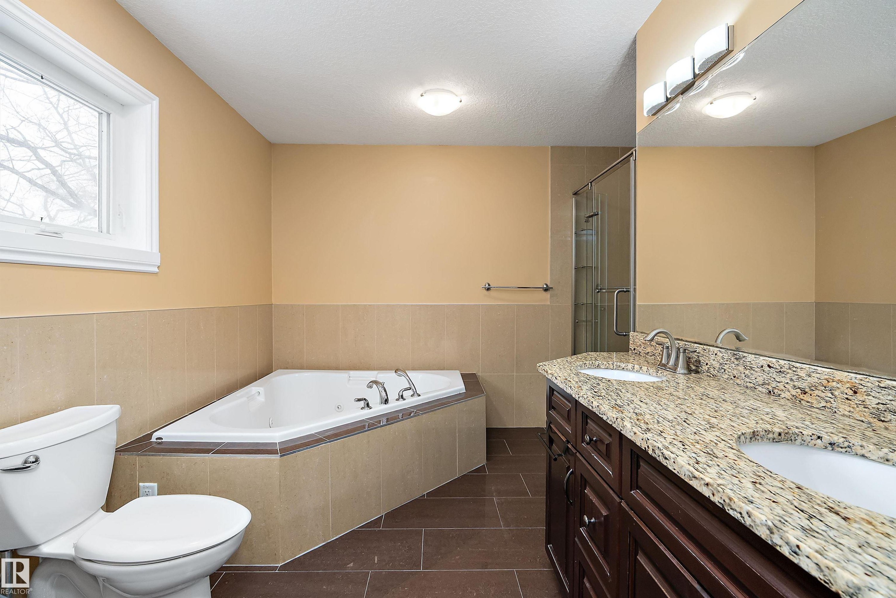 Full bathroom with a bath, dark tile patterned flooring, double vanity, a textured ceiling, and a shower stall - 10623 75 Avenue, Edmonton, AB - Indoor Photo Showing Bathroom