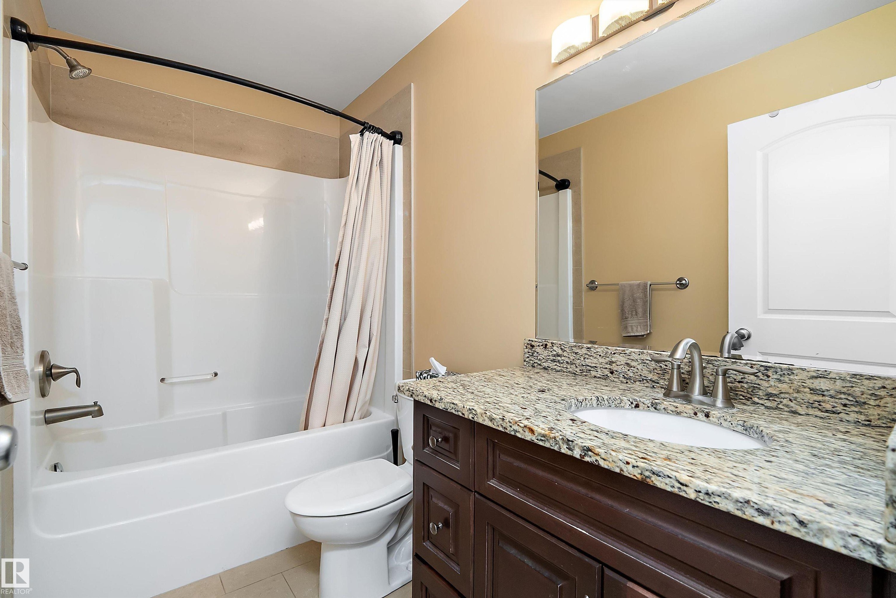 Full bath with vanity, shower / bath combination with curtain, and light tile patterned floors - 10623 75 Avenue, Edmonton, AB - Indoor Photo Showing Bathroom