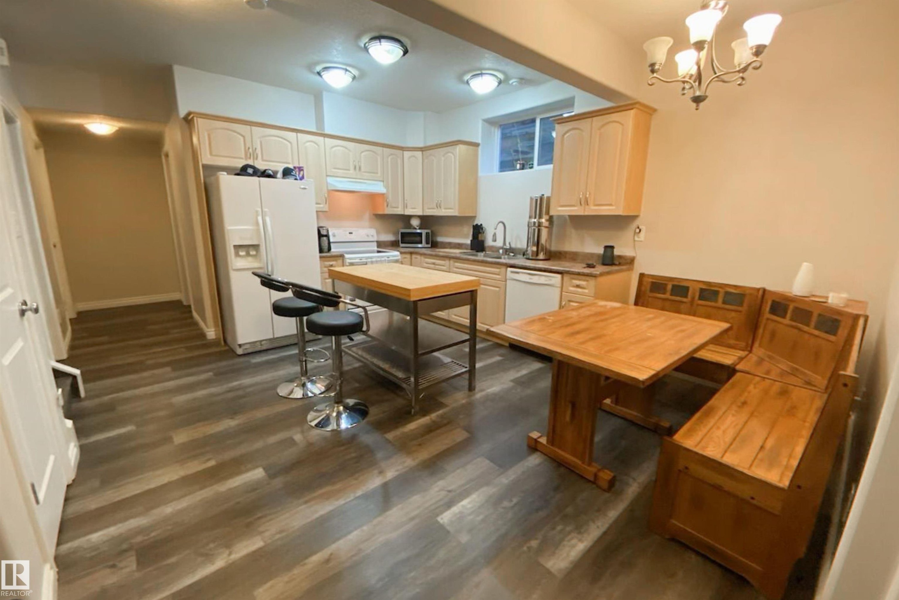 Kitchen featuring white appliances, suspended lighting, dark wood finished floors, and light countertops - 10623 75 Avenue, Edmonton, AB - Indoor Photo Showing Kitchen With Double Sink