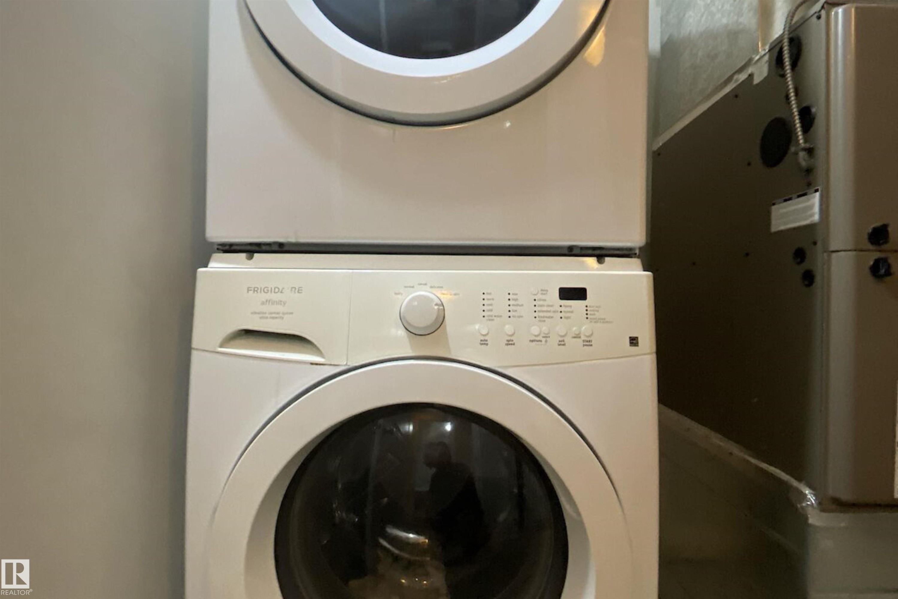 Laundry area featuring heating unit and stacked washer and dryer - 10623 75 Avenue, Edmonton, AB - Indoor Photo Showing Laundry Room