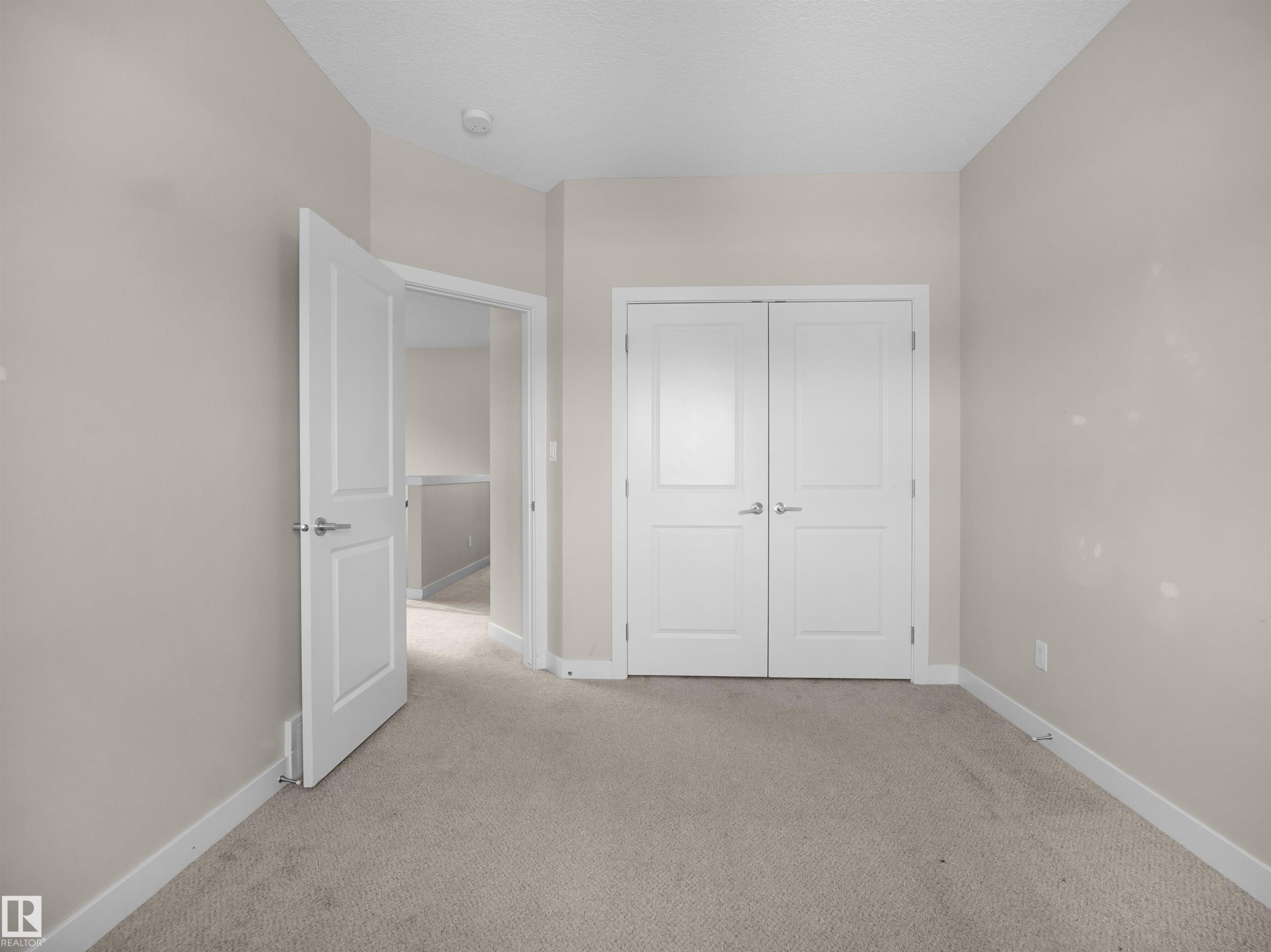 Unfurnished bedroom featuring light colored carpet and a closet - 8921 217 St Nw, Edmonton, AB - Indoor Photo Showing Other Room