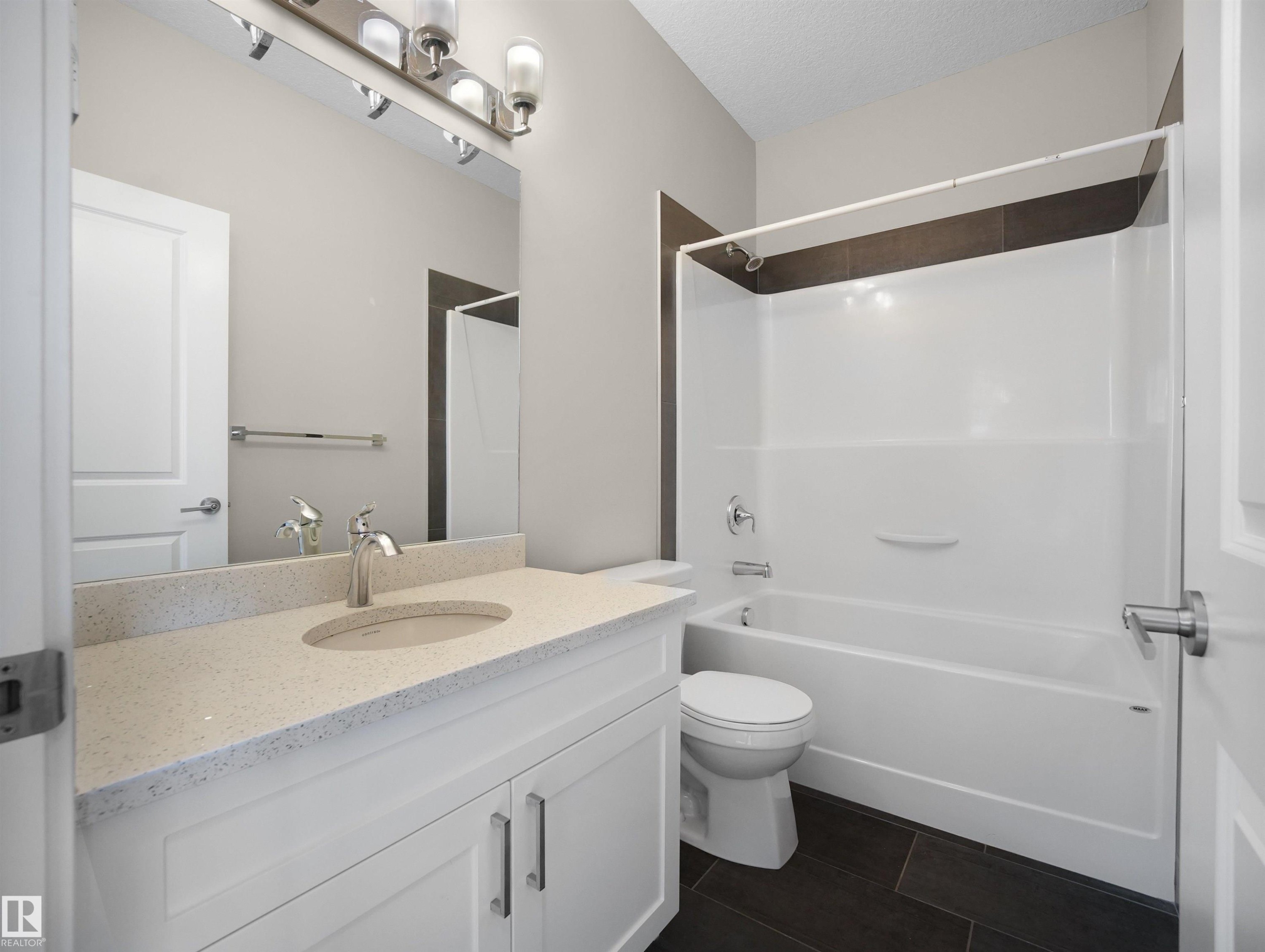 Full bathroom featuring vanity, shower / bath combination, dark tile patterned flooring, and a textured ceiling - 8921 217 St Nw, Edmonton, AB - Indoor Photo Showing Bathroom