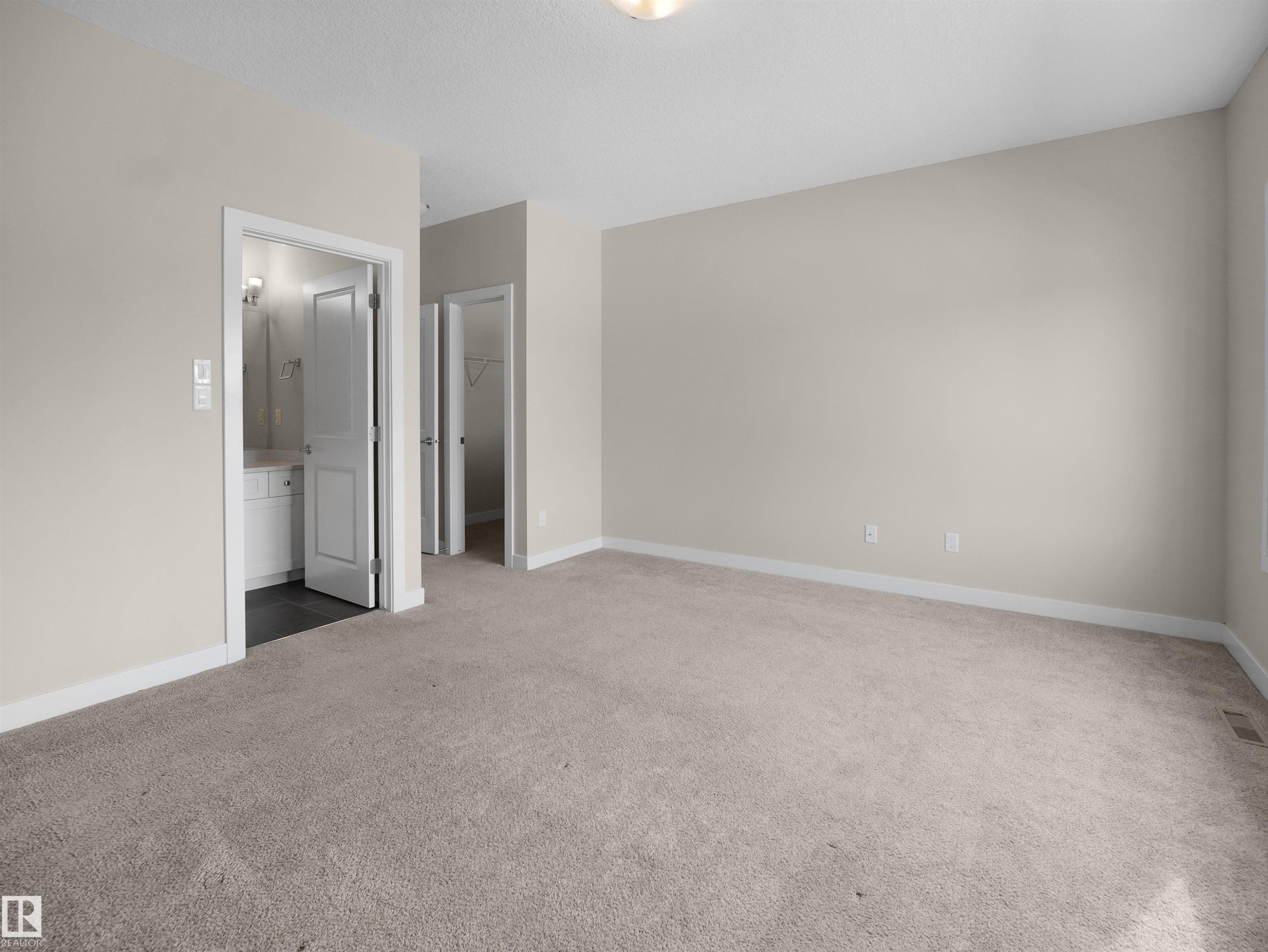 Unfurnished bedroom featuring light colored carpet, a walk in closet, and ensuite bathroom - 8921 217 St Nw, Edmonton, AB - Indoor Photo Showing Other Room