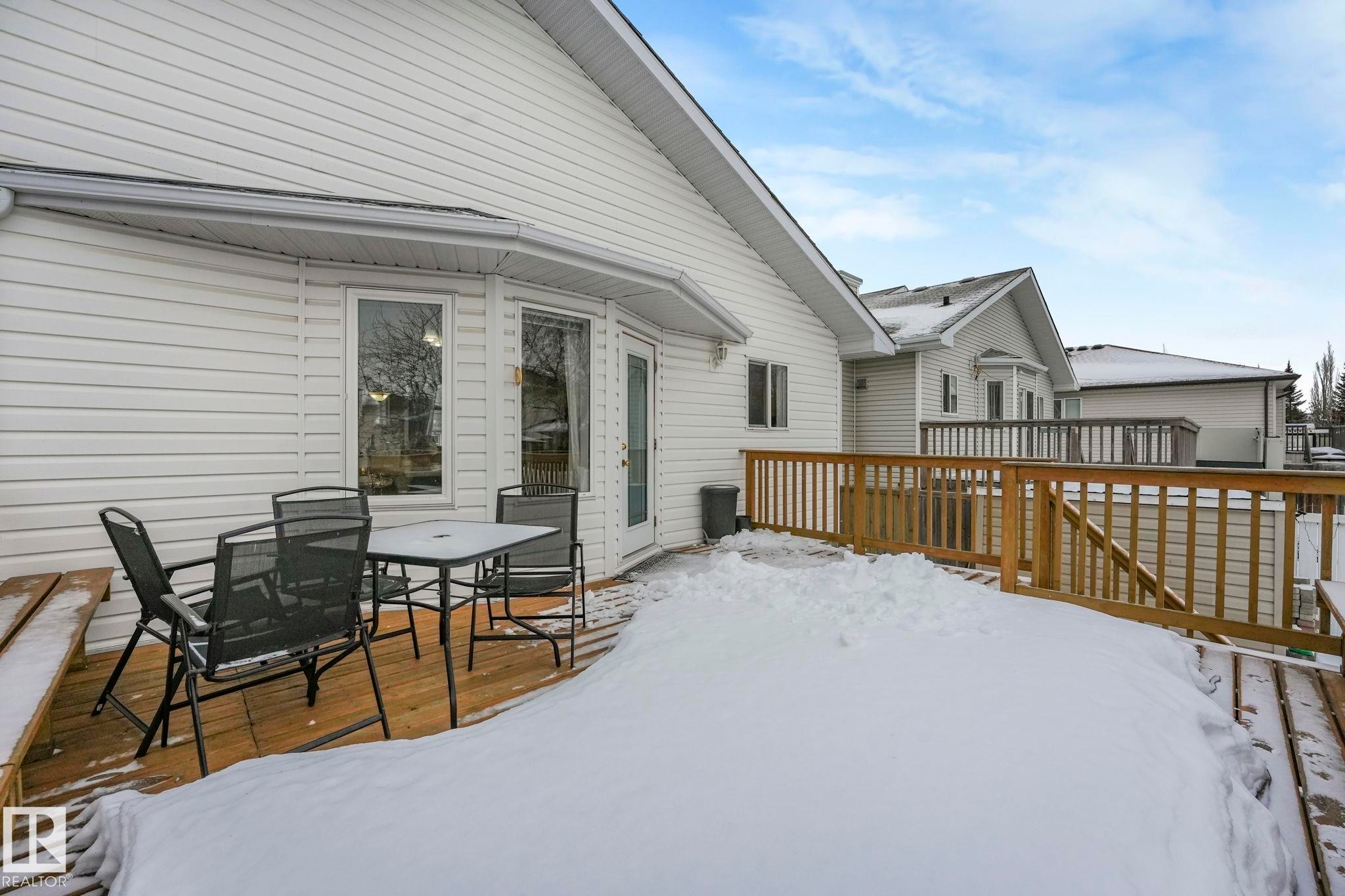 Snow covered patio with a wooden deck and outdoor dining area - 4720 150 Avenue, Edmonton, AB - Outdoor With Deck Patio Veranda With Exterior