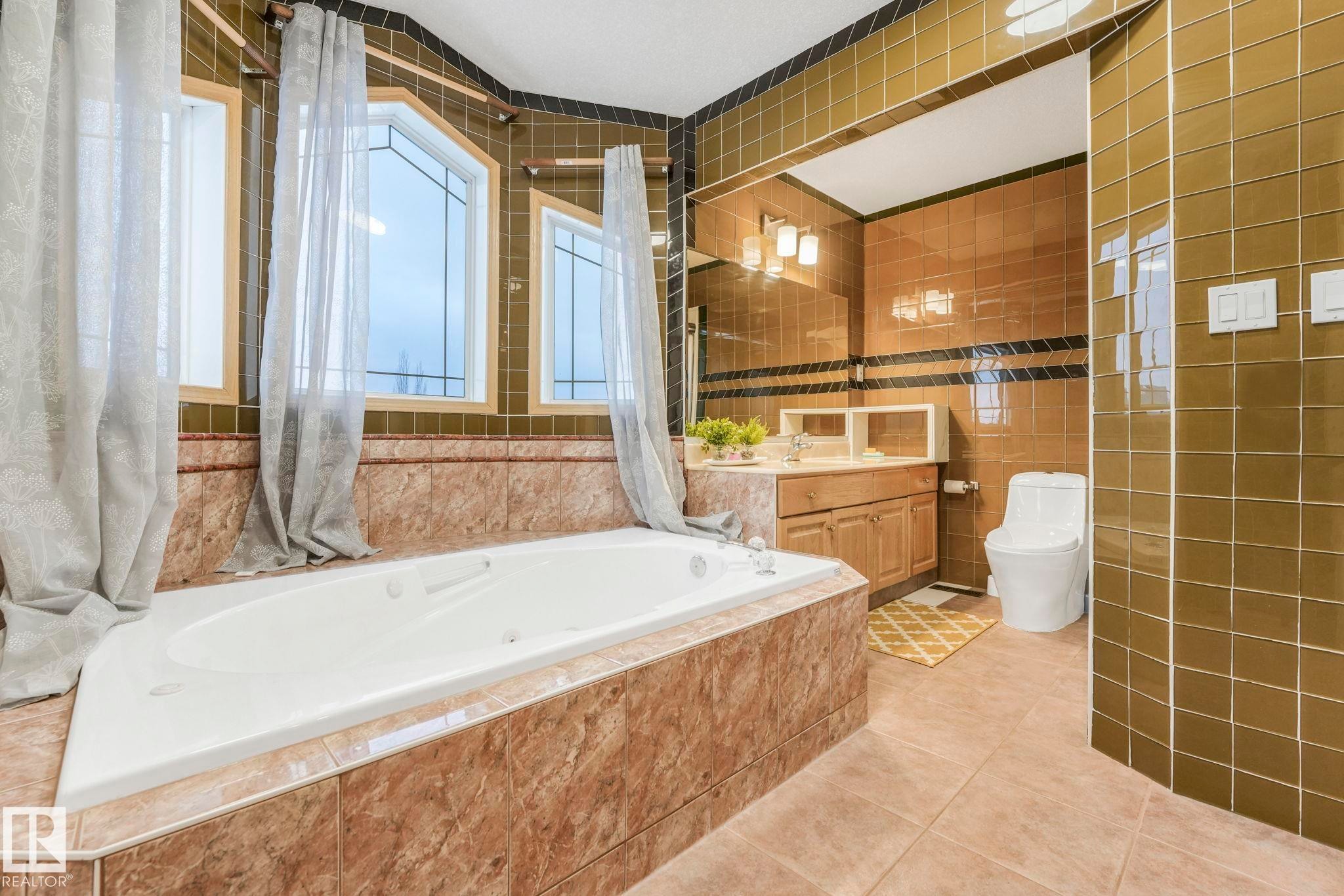 Bathroom with tile walls, vanity, light tile patterned floors, and tiled tub - 4720 150 Avenue, Edmonton, AB - Indoor Photo Showing Bathroom