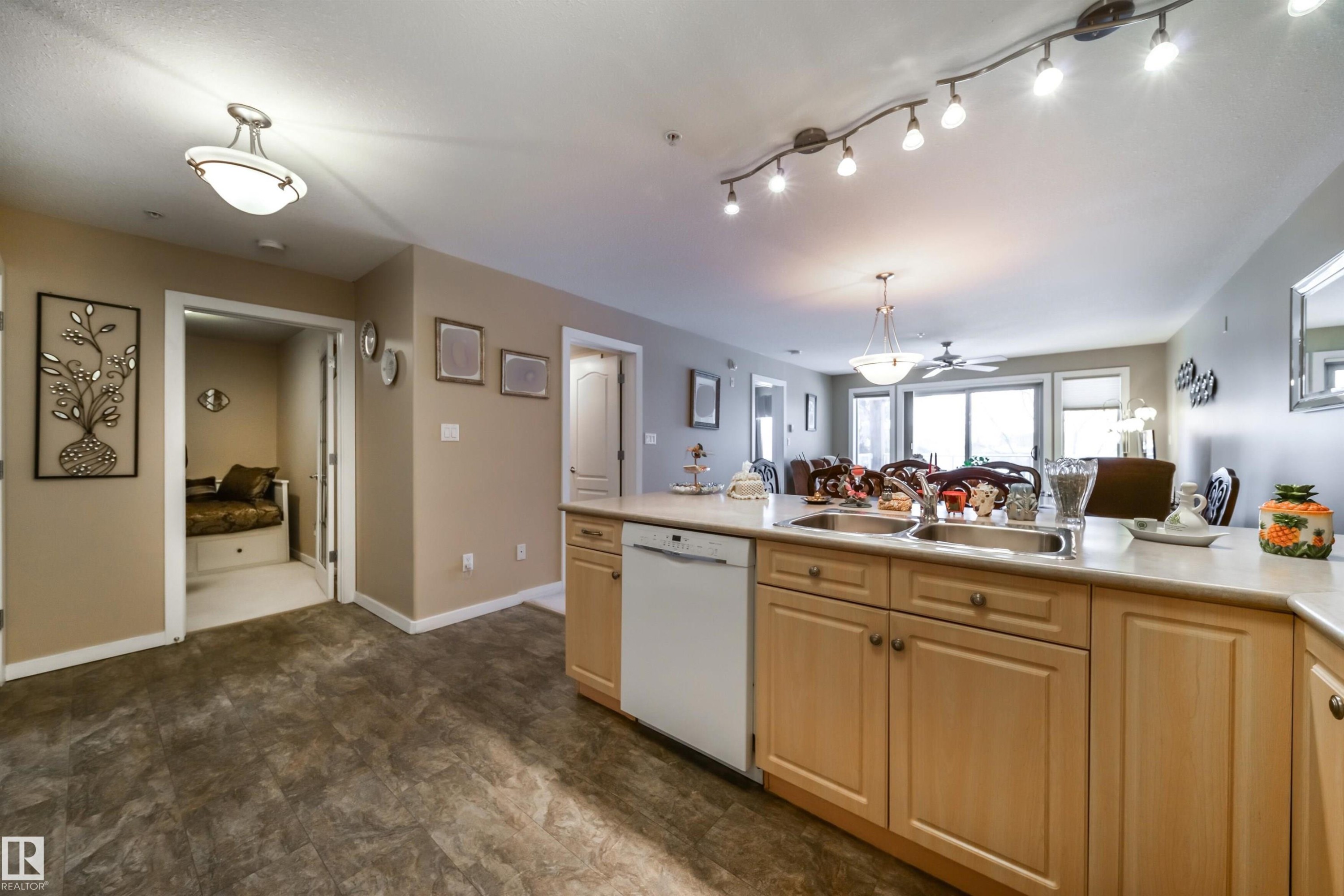 Kitchen with light countertops, white dishwasher, light wood finish cabinetry, open floor plan, and hanging light fixtures - 237 278 Suder Greens Drive, Edmonton, AB - Indoor Photo Showing Bathroom