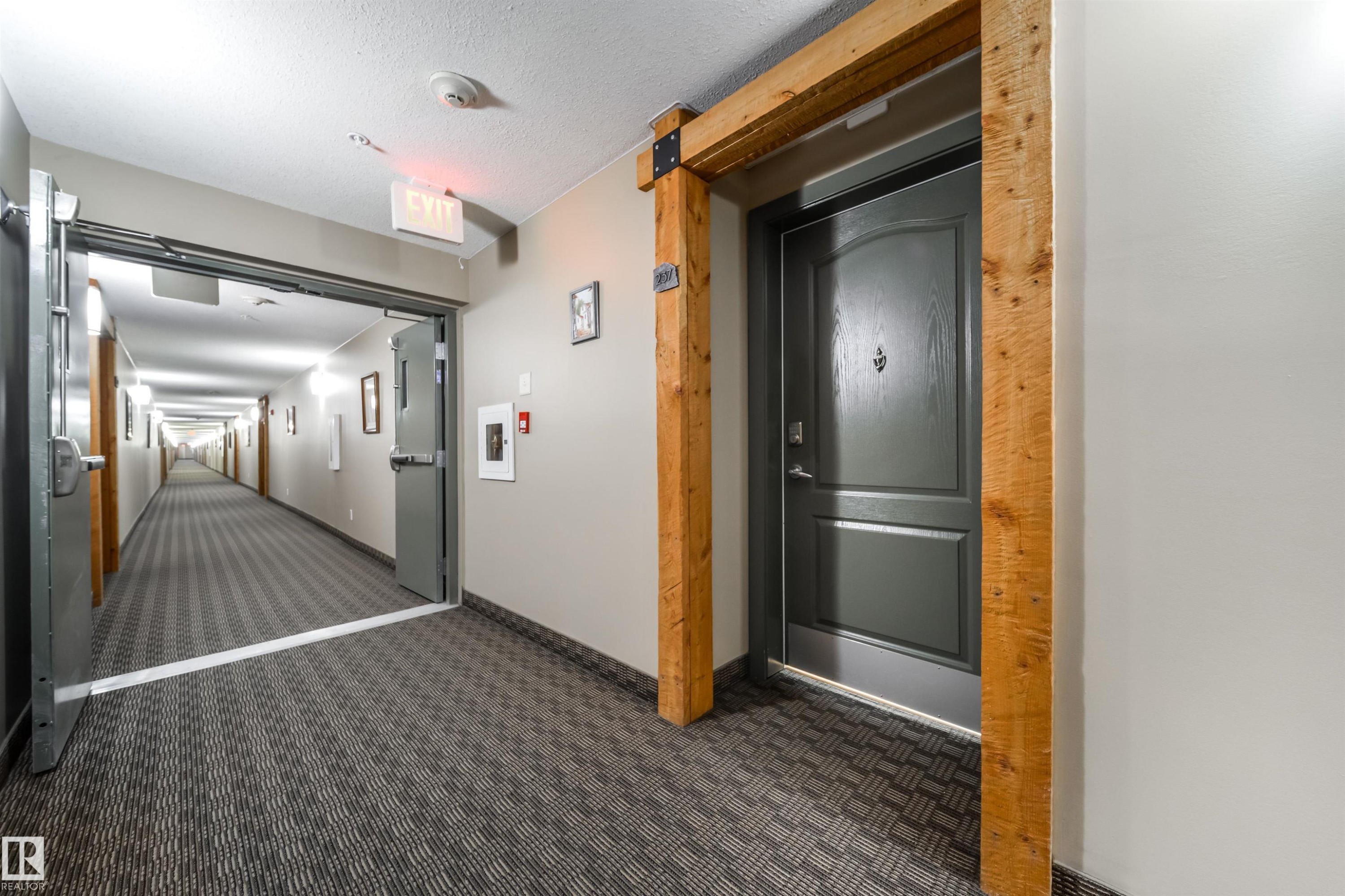 Hallway with a barn door, dark carpet, and a textured ceiling - 237 278 Suder Greens Drive, Edmonton, AB - Indoor Photo Showing Kitchen
