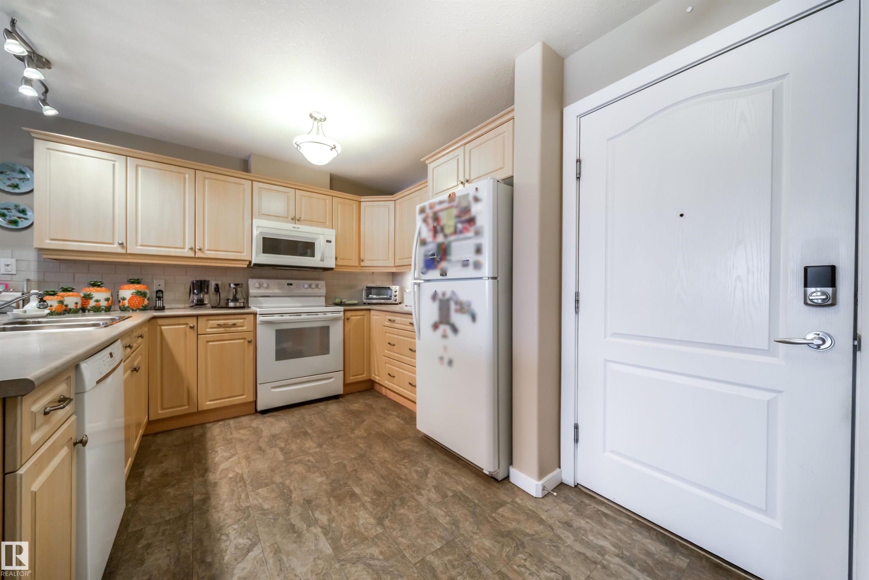 Kitchen with white appliances, light wood finish cabinetry, decorative backsplash, and light countertops - 237 278 Suder Greens Drive, Edmonton, AB - Indoor Photo Showing Kitchen