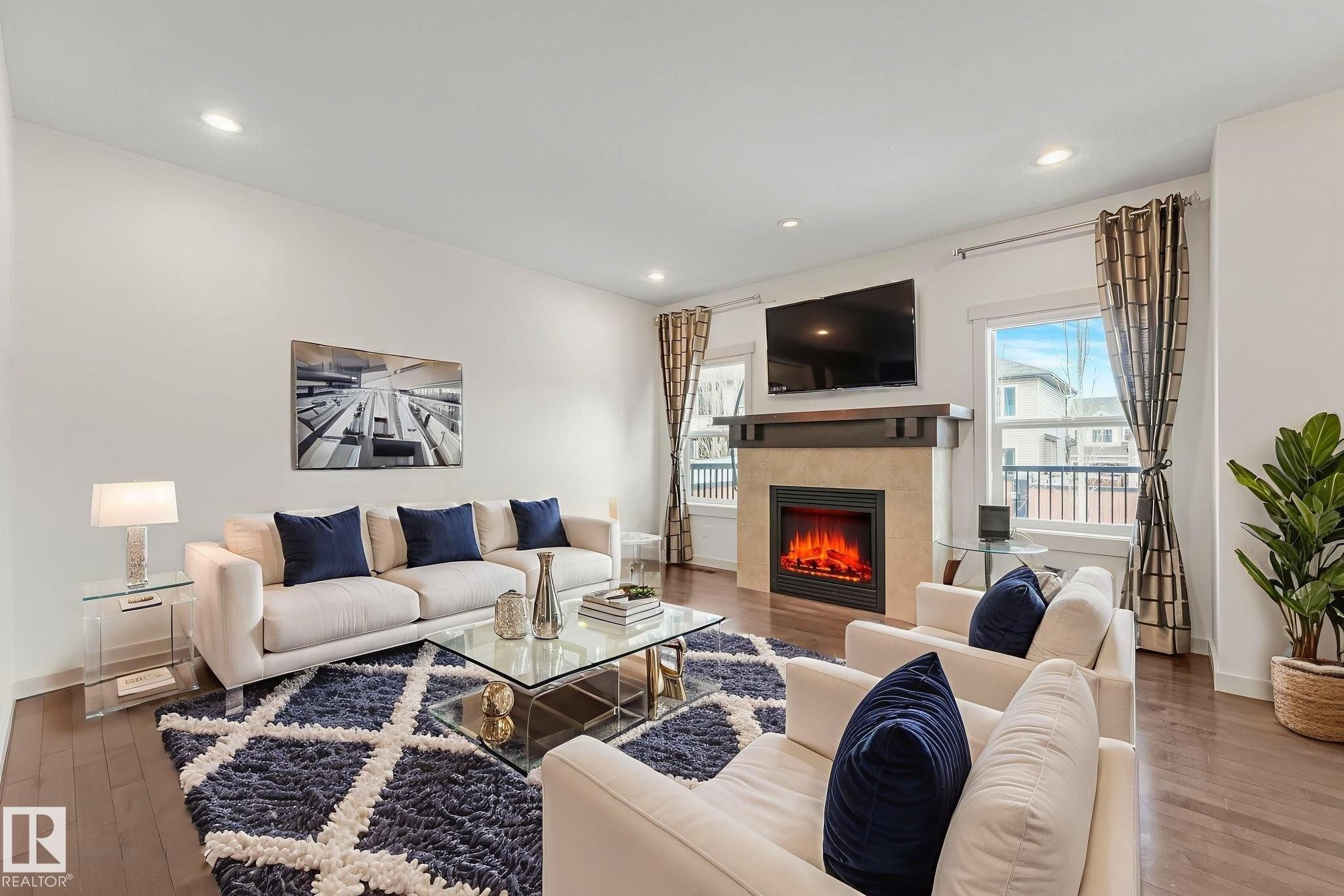 Living room with hardwood / wood-style floors, plenty of natural light, a tile fireplace, and recessed lighting - 1548 36 Avenue, Edmonton, AB - Indoor Photo Showing Living Room With Fireplace