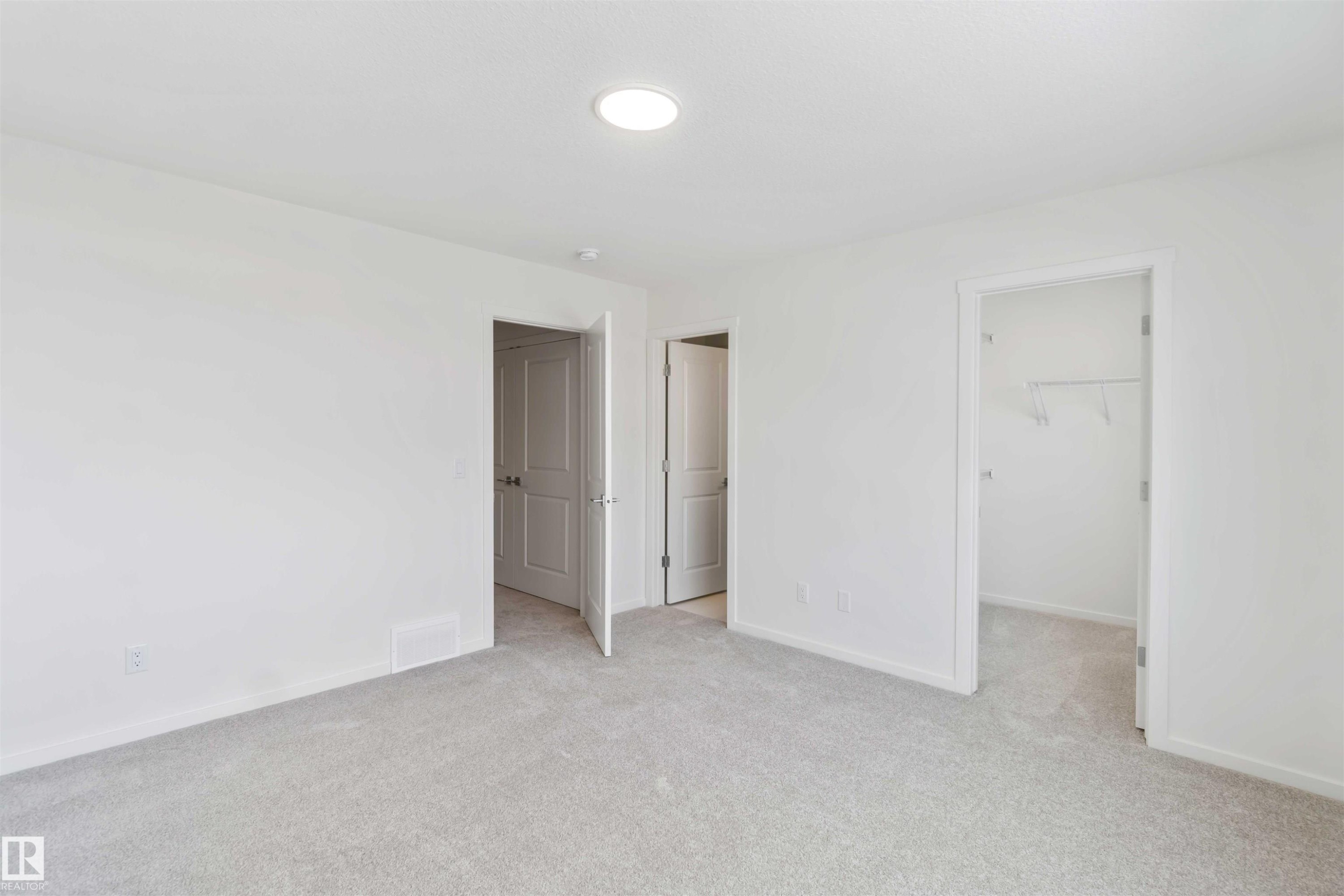 Unfurnished bedroom with light carpet and a walk in closet - 2467 Alces Link Link, Edmonton, AB - Indoor