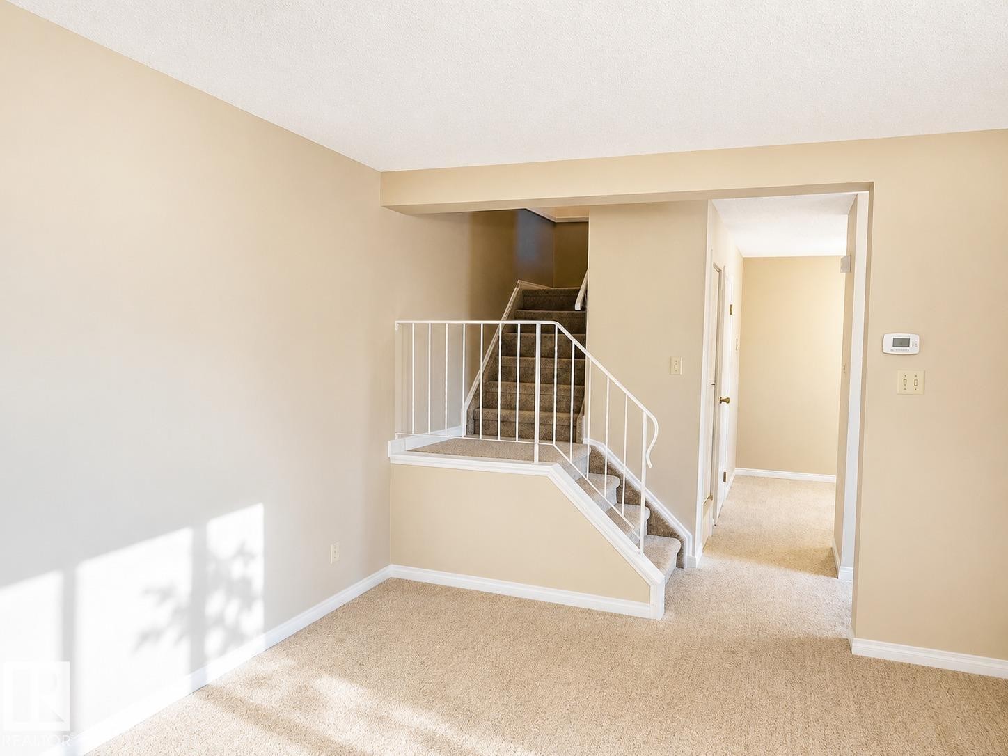Carpeted staircase with white metal railing, neutral wall tones, and white trim - 223 Kaskitayo Crest, Edmonton, AB - Indoor Photo Showing Other Room