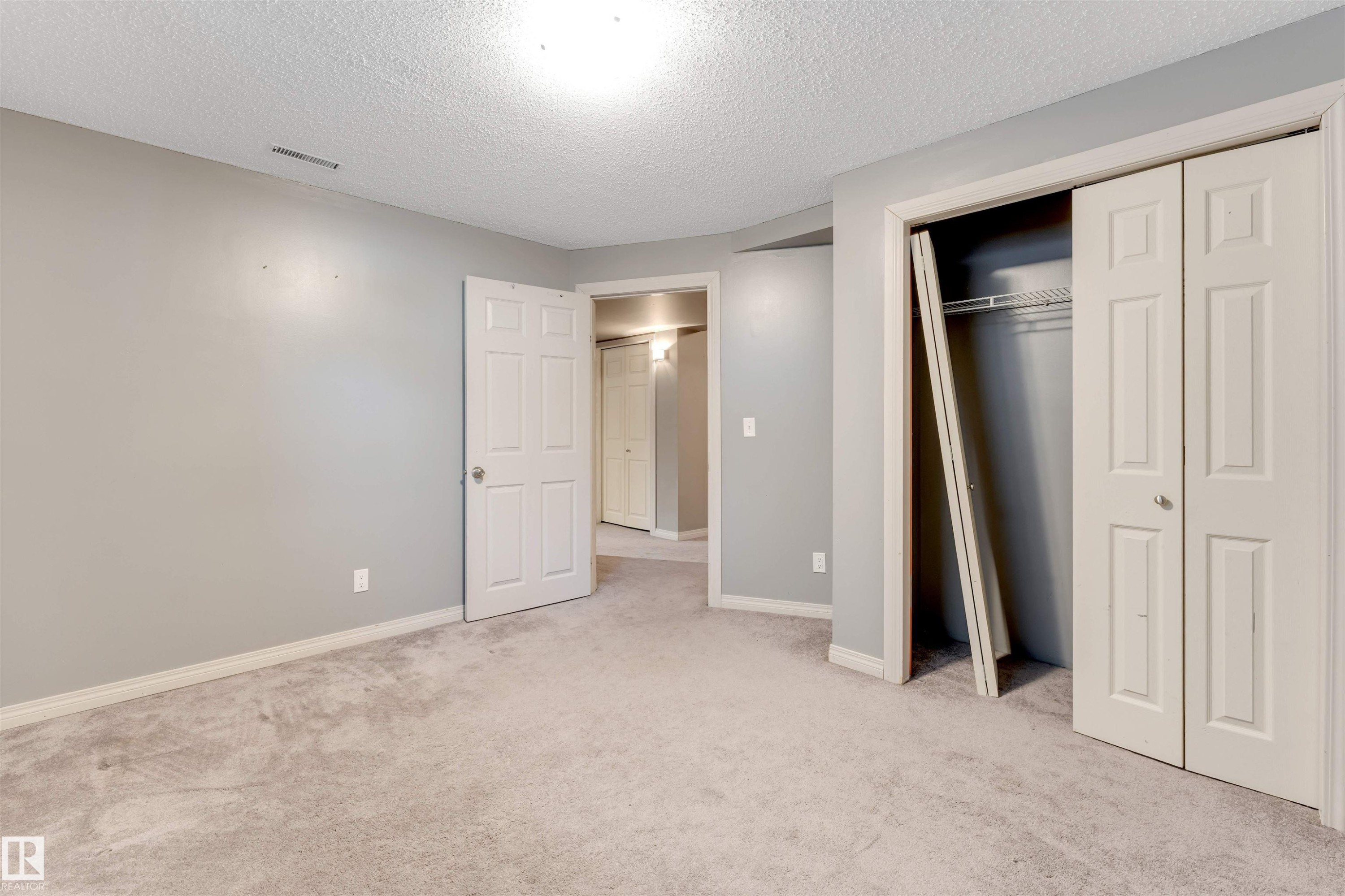 Unfurnished bedroom featuring light carpet, a textured ceiling, and a closet - 1157 37 Avenue, Edmonton, AB - Indoor Photo Showing Other Room