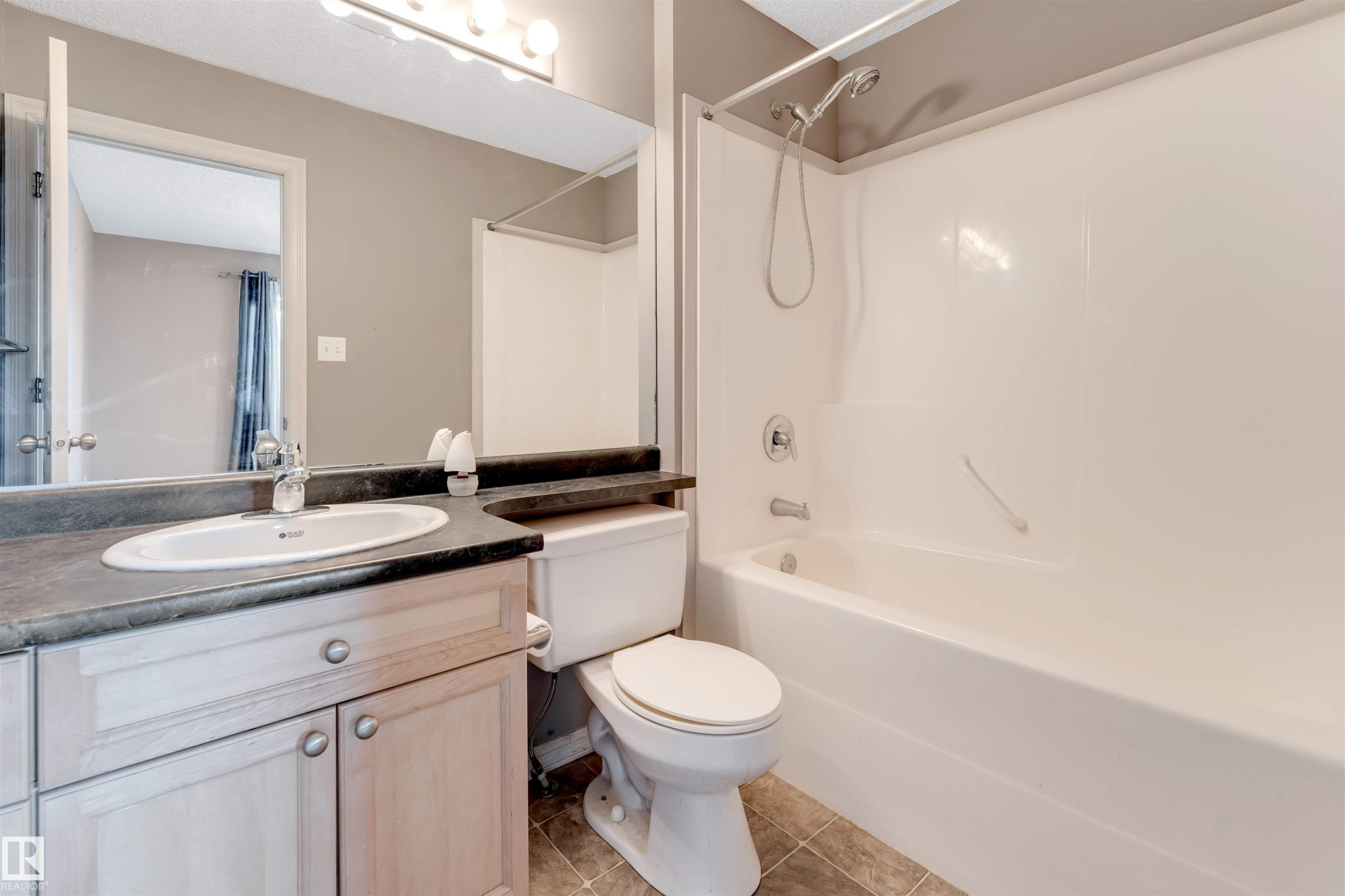 Full bath featuring vanity, shower combination, and light tile patterned floors - 1157 37 Avenue, Edmonton, AB - Indoor Photo Showing Bathroom